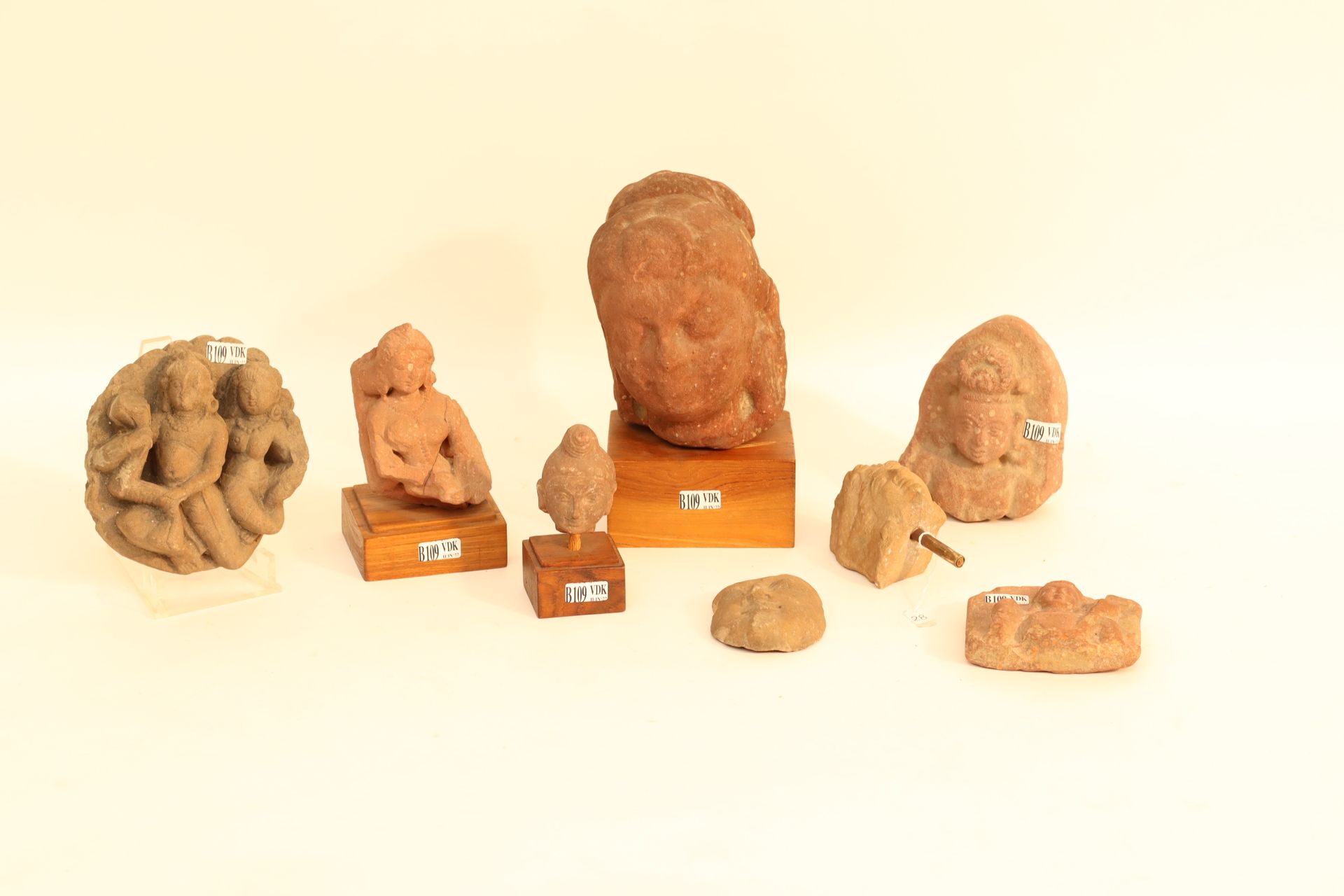 Null 一套8件红色和棕色砂岩雕塑，包括 "头像"、"胸像 "和描绘 "神灵 "的高浮雕。古代印度的作品。(四个放在一个木质底座上）。(*和**)。高度：从6&hellip;