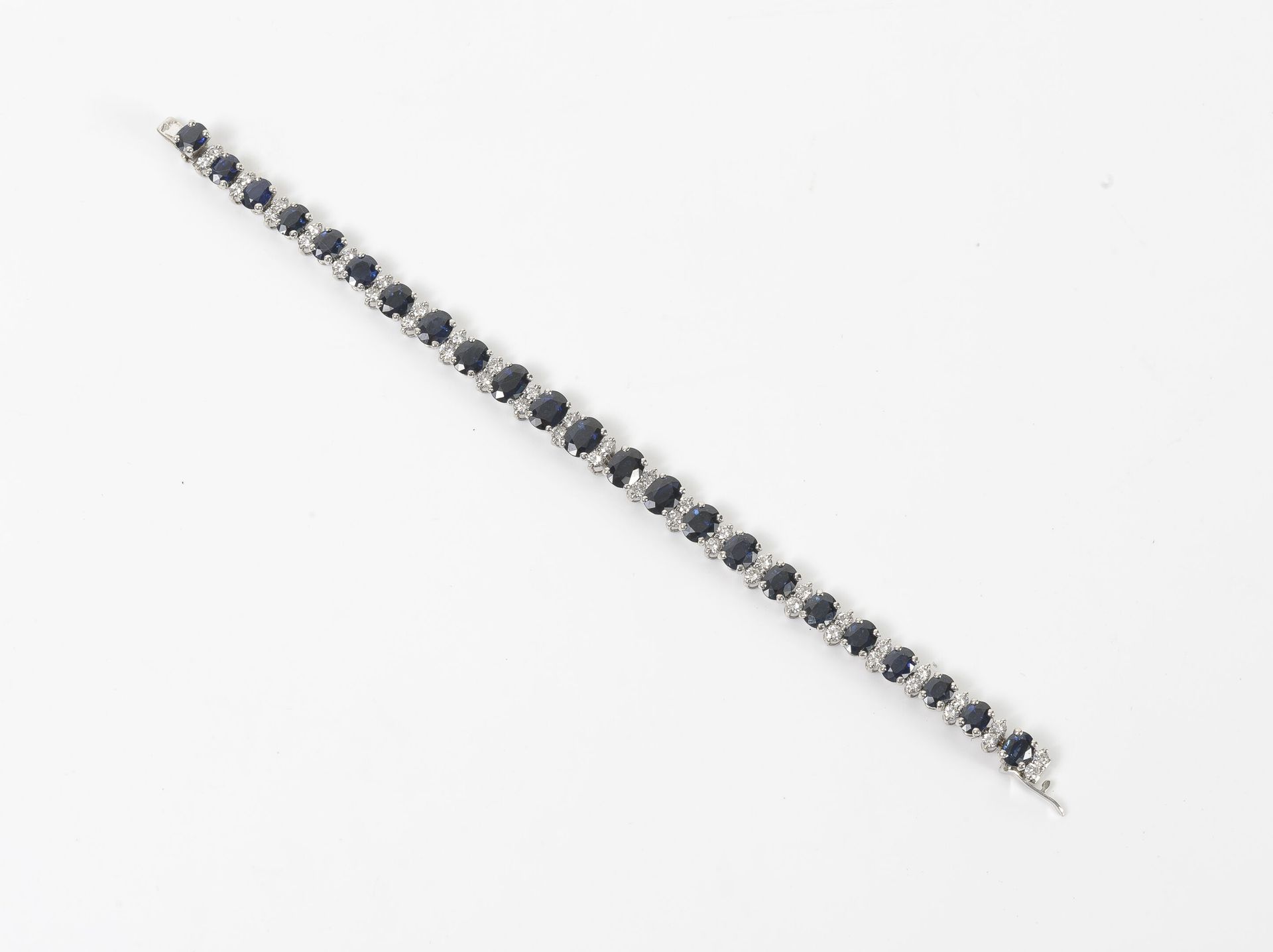 Null 
，白金（750）线型手镯，爪式镶嵌二十三颗刻面椭圆形蓝宝石和明亮式切割钻石。
，毛重：24.3g。- 长度：17厘米。