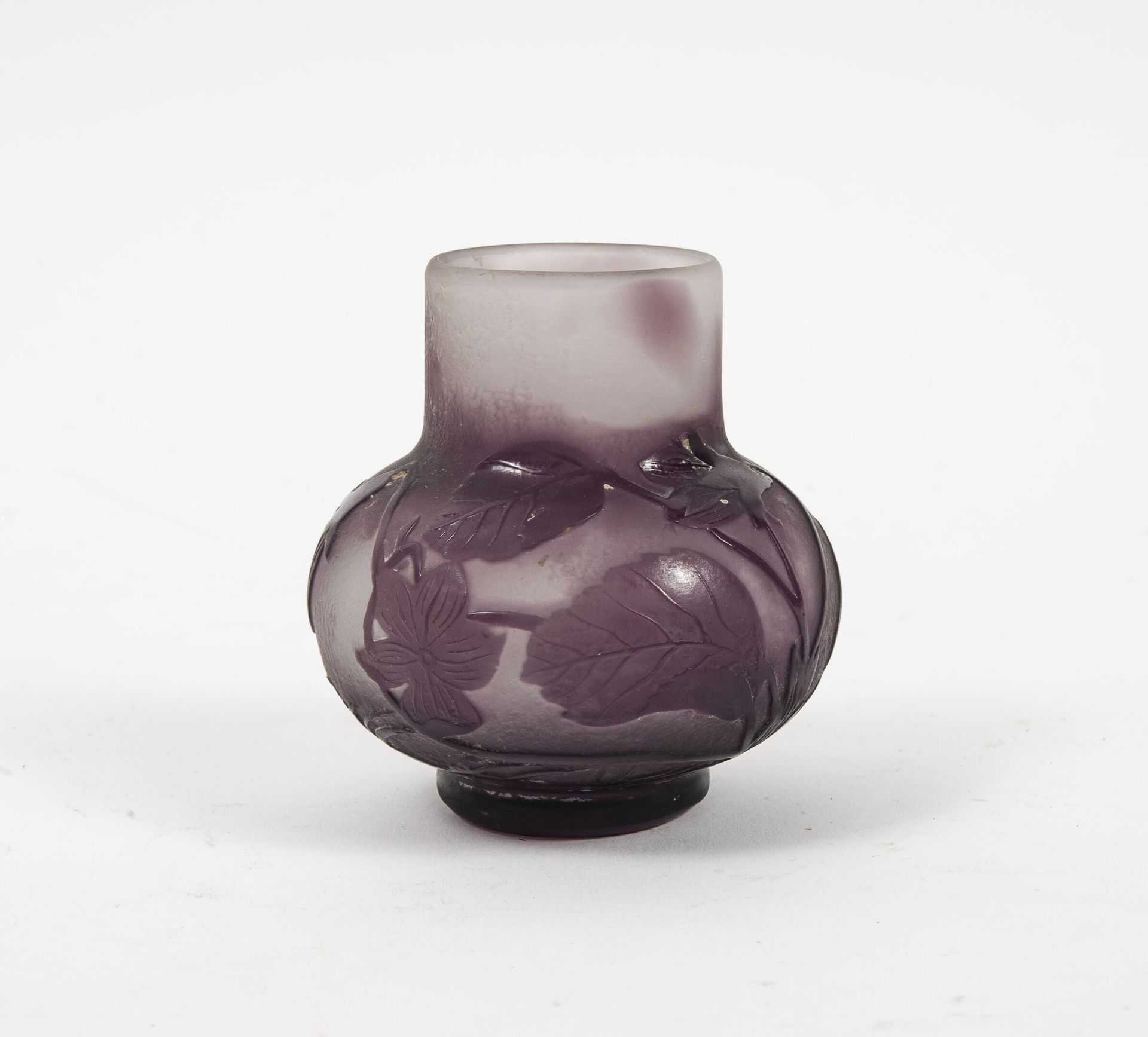 Etablissements GALLÉ 小花瓶，小跟头上的圆体，直颈。

紫色内衬玻璃中的证明，淡紫色至白色背景。

酸蚀浮雕的紫罗兰和草叶的装饰。

签名。&hellip;