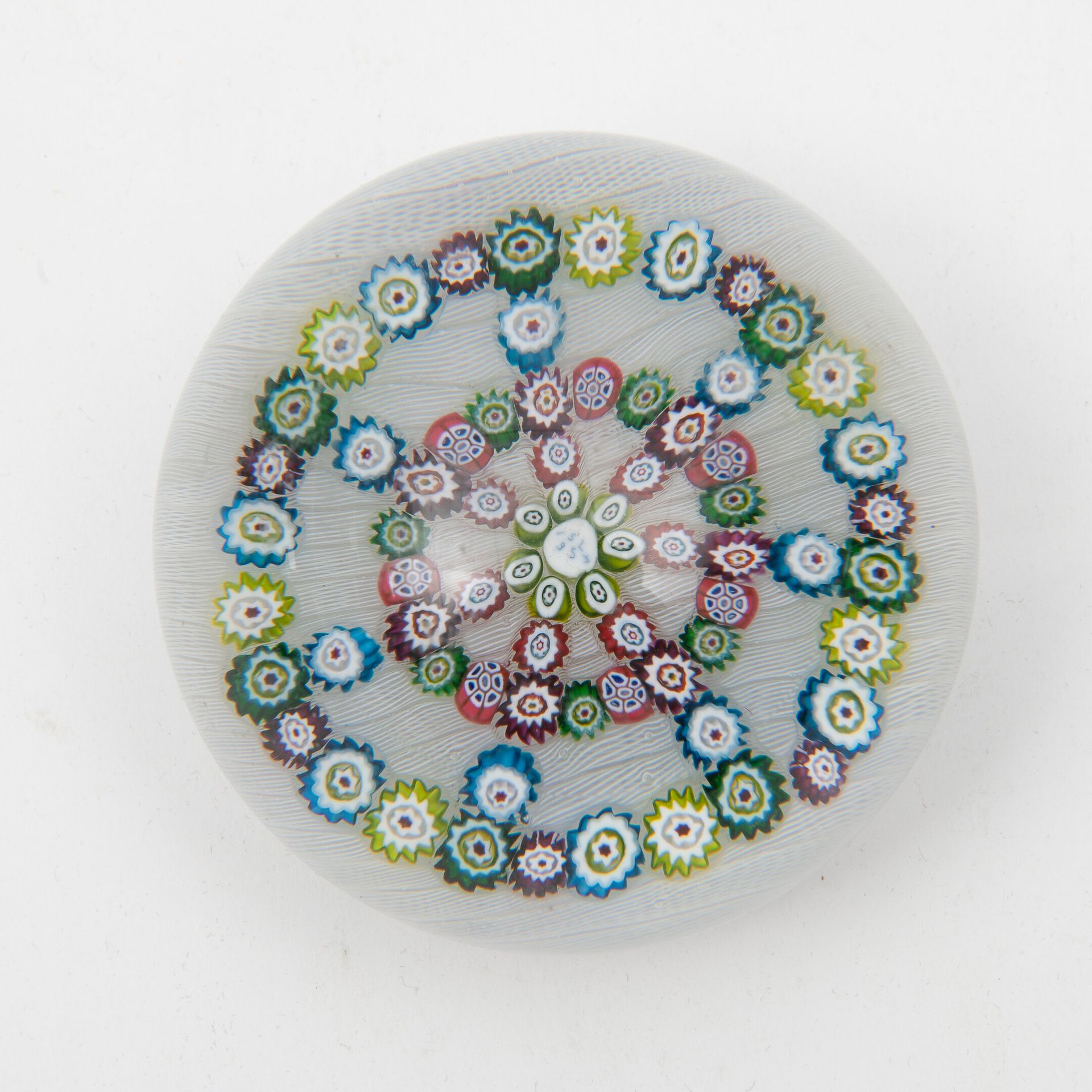 SAINT-LOUIS 无色的水晶球形成一个镇纸，上面装饰着五颜六色的糖果，在花丝背景上排列成一个圆圈和星星。

底座下有 "Cristal Saint-Lou&hellip;