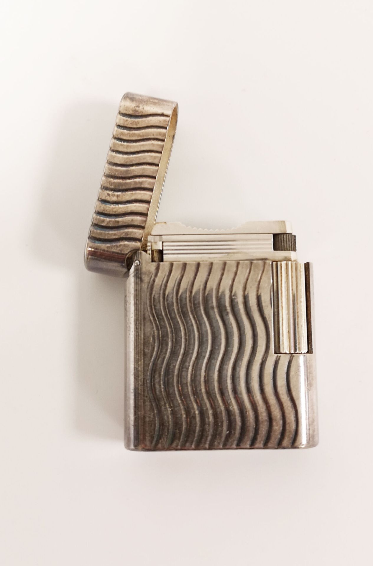 S.T. DUPONT Silver-plated metal lighter with undulating vertical incised lines.
&hellip;