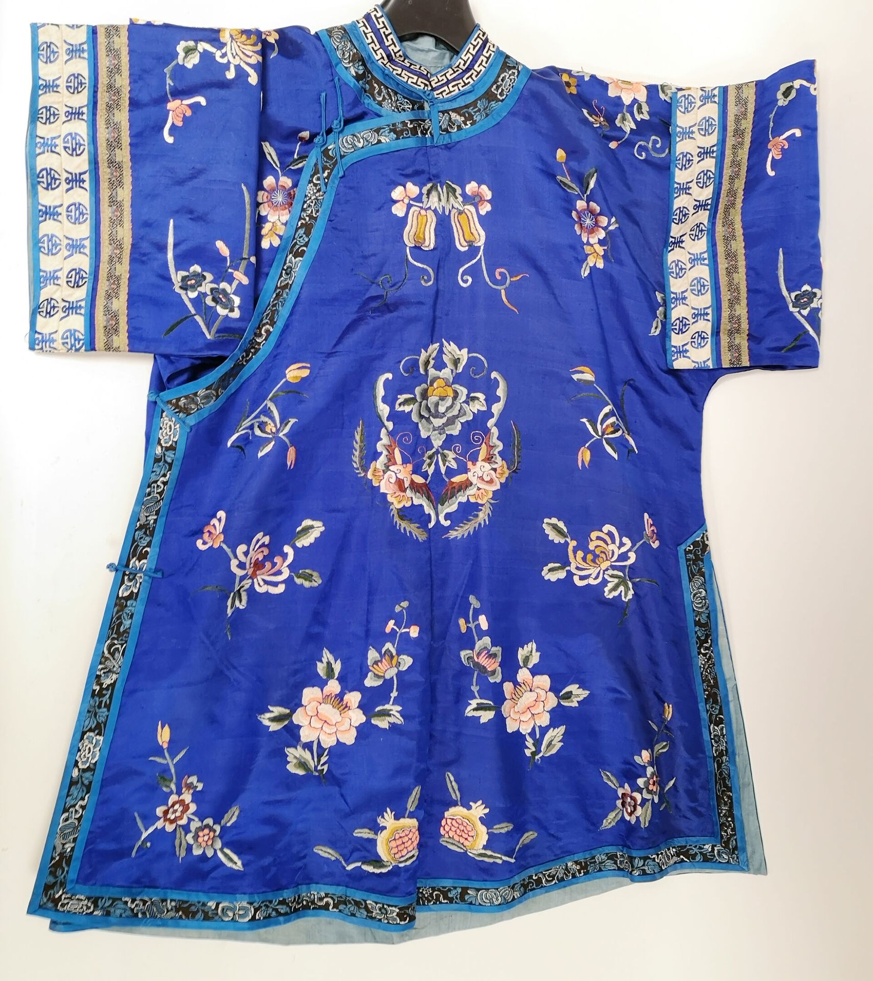 CHINE, début du XXème siècle - 蓝色丝绸长衫，绣有花卉图案和多色蝴蝶。

H.89厘米 - 宽度：117厘米。 

有污点，一些线&hellip;