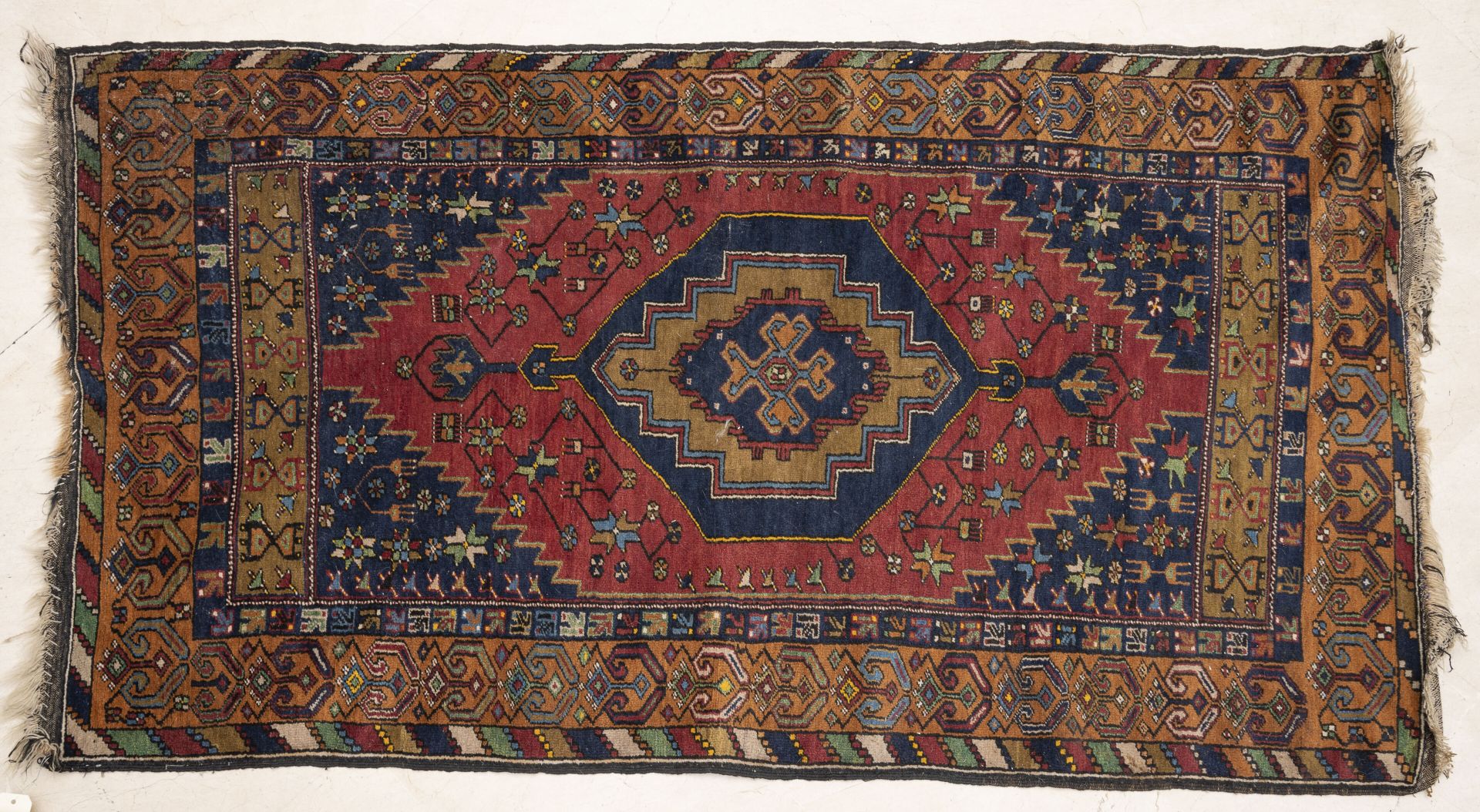 TURQUIE, Yahyali, XXème siècle 宝丽金羊毛地毯，具有风格化的几何图案，红场背景上有蓝色的钻石图案，四个蓝色的横幅上有半星，双叉和三&hellip;