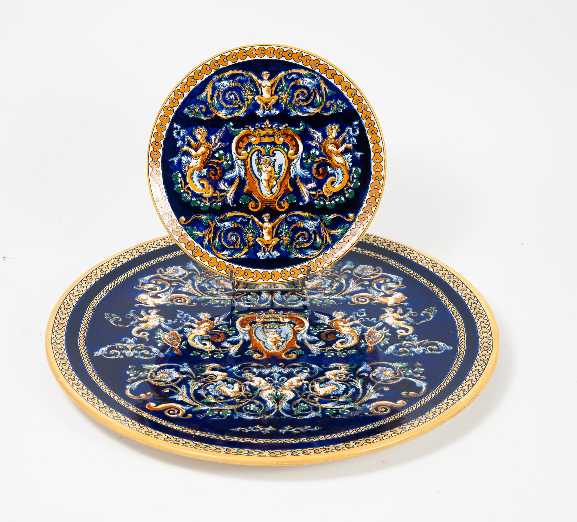 GIEN 两个圆形的陶器，在蓝色的背景上装饰着怪兽，中心是以侯爵的王冠为顶的图样。

直径：25.5和46厘米。

小的划痕和磨损。