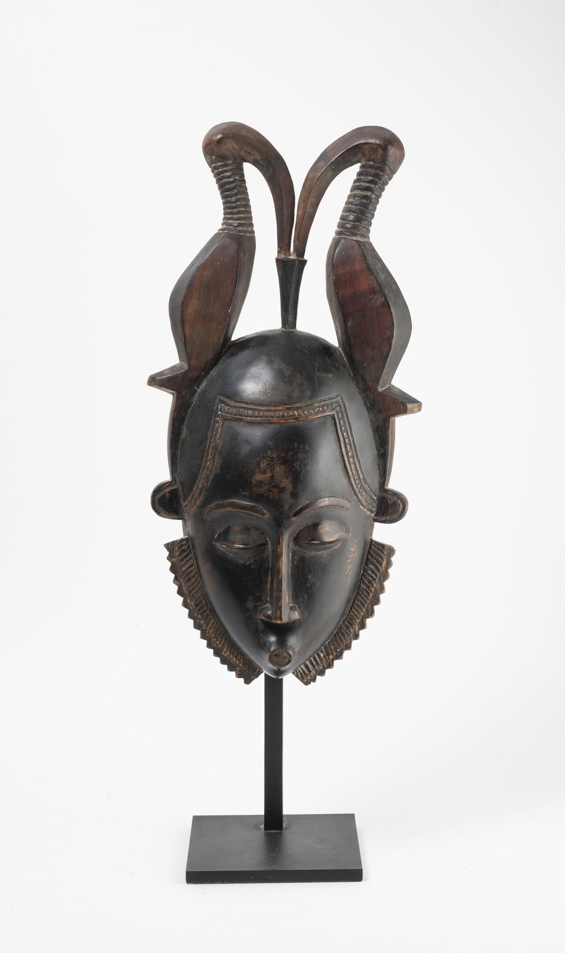 Côte d'Ivoire, Baoulé 雕刻和铜化的木制面具，头部有两只鸟对峙。

H.41厘米。

总高度：56厘米。

基地。

轻微磨损。