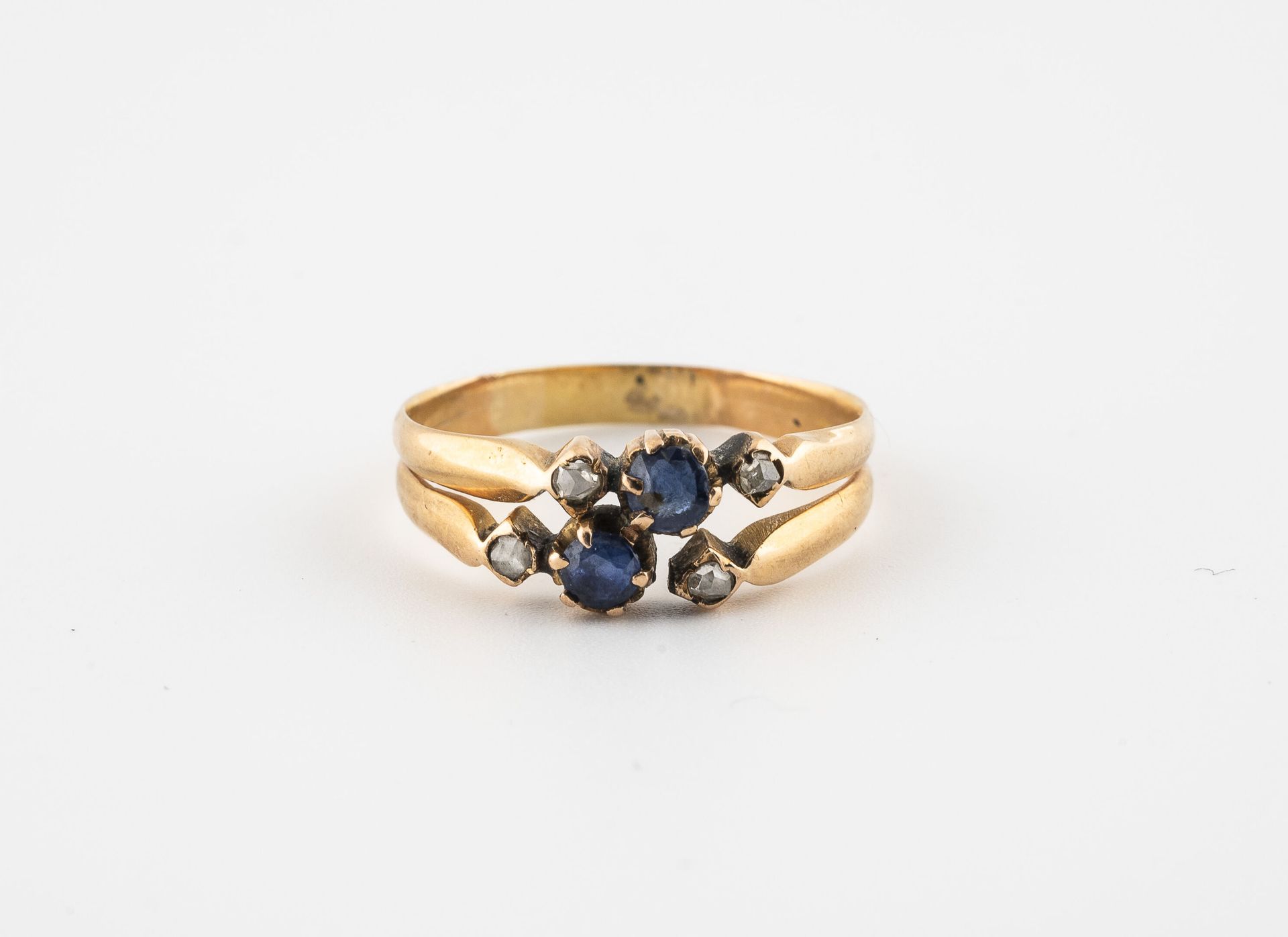 Null 黄金（585）戒指，爪式镶嵌两颗刻面蓝宝石，周围是种子式镶嵌的四颗玫瑰切割钻石。

毛重：2.8克。- 手指大小：58。

刮伤。