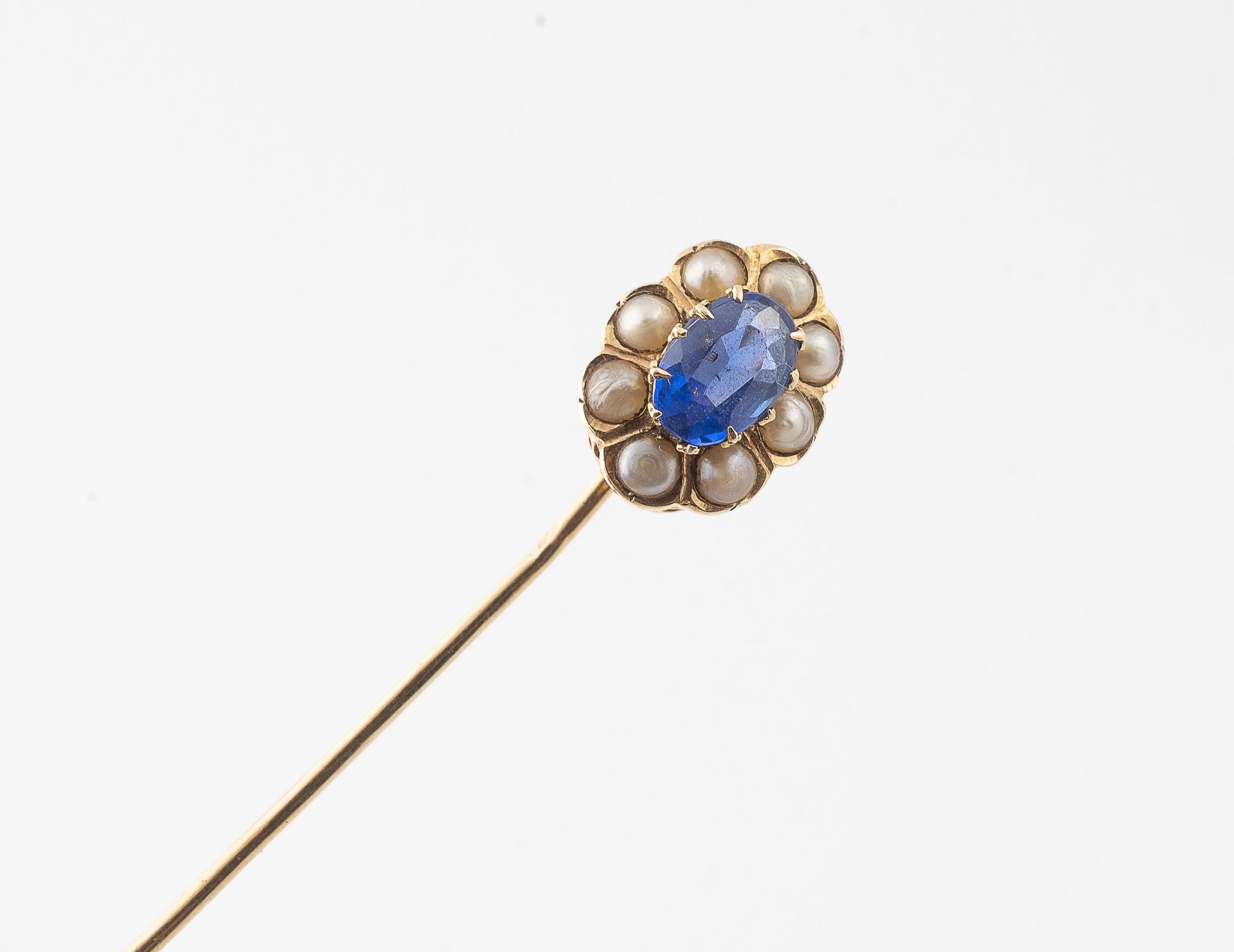 Null 黄金（750）领带针，中心是一个模仿椭圆形刻面蓝宝石的蓝色玻璃石榴石，用爪子镶嵌，周围有白色马贝珍珠。

毛重：1.1克。- 长度：63毫米。

刮伤&hellip;