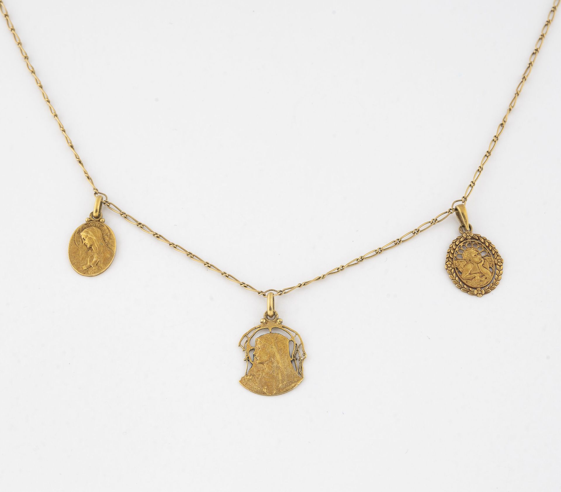 Null 黄金（750）颈链，有花纹缝制，装有三枚宗教奖章。

弹簧环扣。

反面有刻字或日期。

重量：8.4克。- 长度：45厘米。

钮扣有待修订。