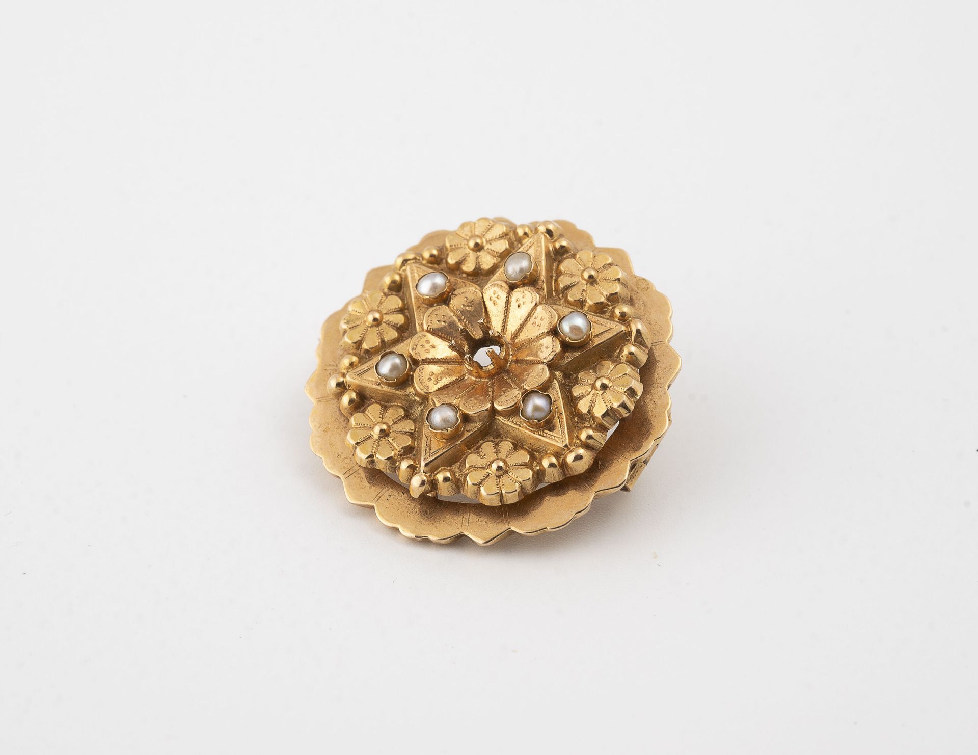 Null 黄金（750）圆形胸针，带小白珍珠种子。

黄金针（750）。

毛重：1.9克。- 直径：2.3厘米。

有一颗珍珠不见了。
