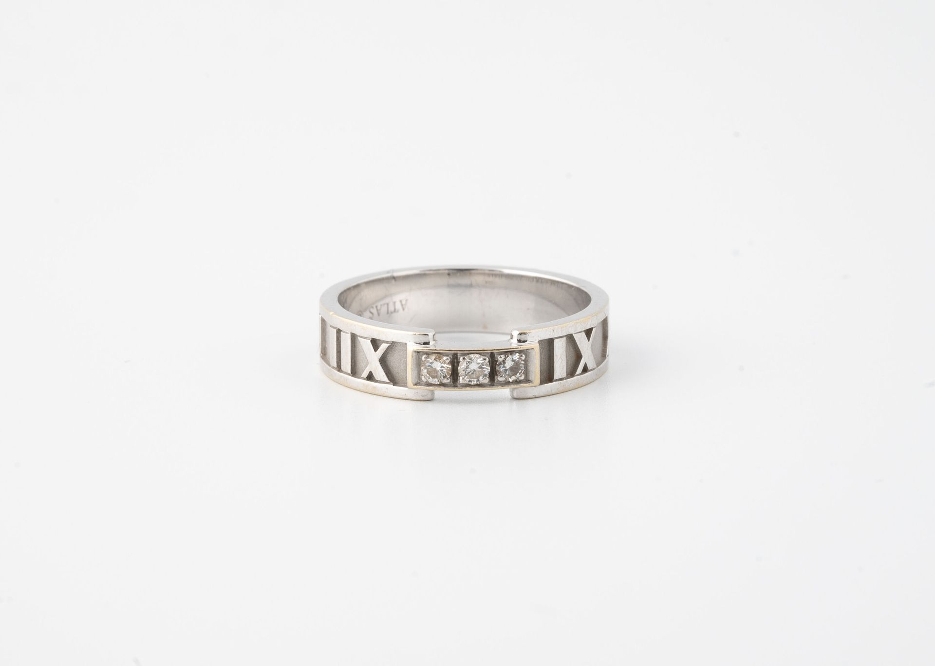 TIFFANY & CO, Atlas 白金（750）结婚戒指，部分镶嵌罗马数字，中心是三颗爪形切割的小钻石。

在戒指上签名。 

毛重：6.1克 - 手指大&hellip;