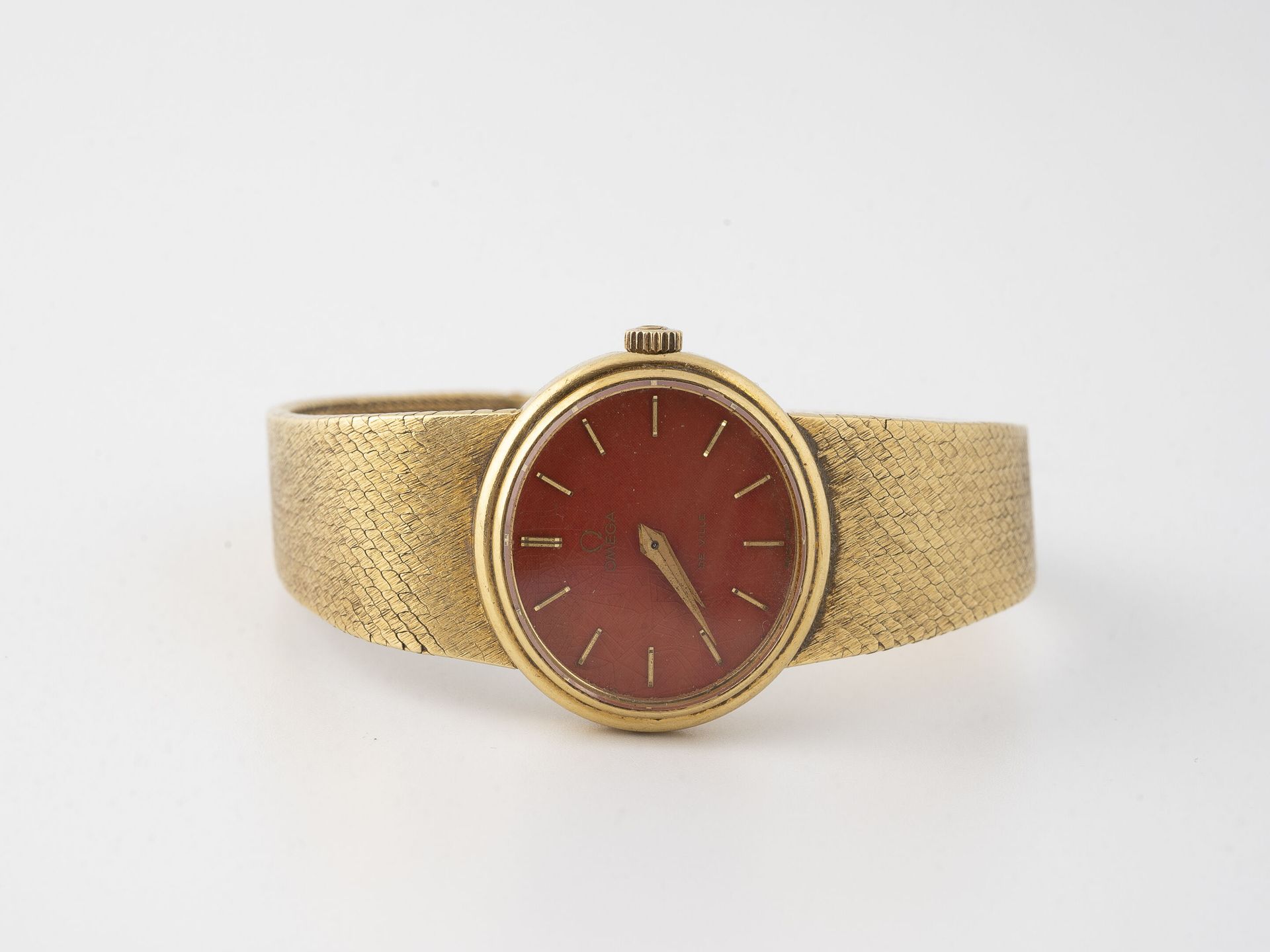 OMEGA Lady's wristwatch in yellow gold (750).

Oval case.

Dial with cinnabar ba&hellip;