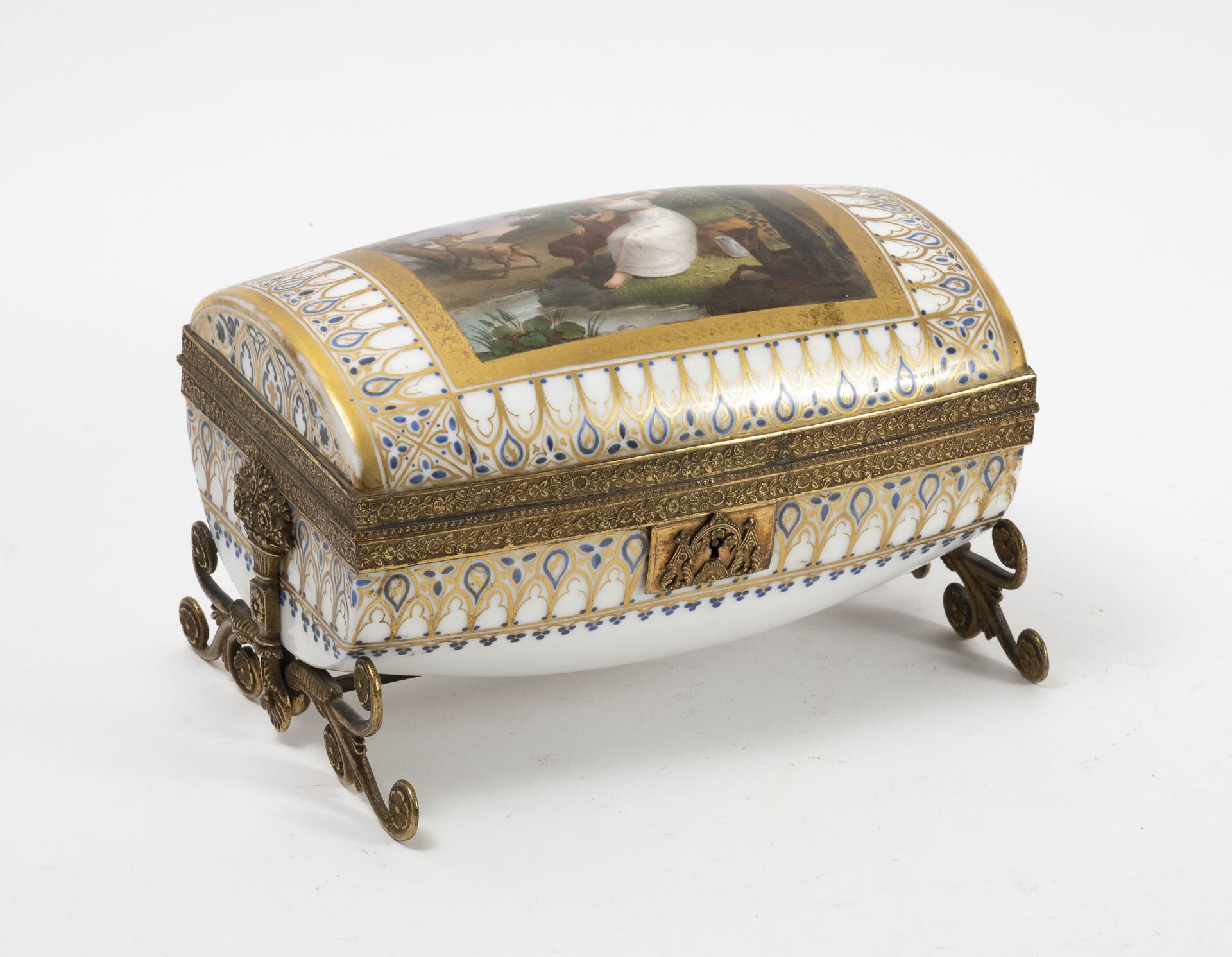 Null 一个小的扁平桶状瓷盒，有一个鎏金的金属框架。 
盖子上的彩绘装饰是一个在保护区内的风景中带着山羊的女人，周围是蓝色和镀金的披针形楣。 
19世纪。 
&hellip;