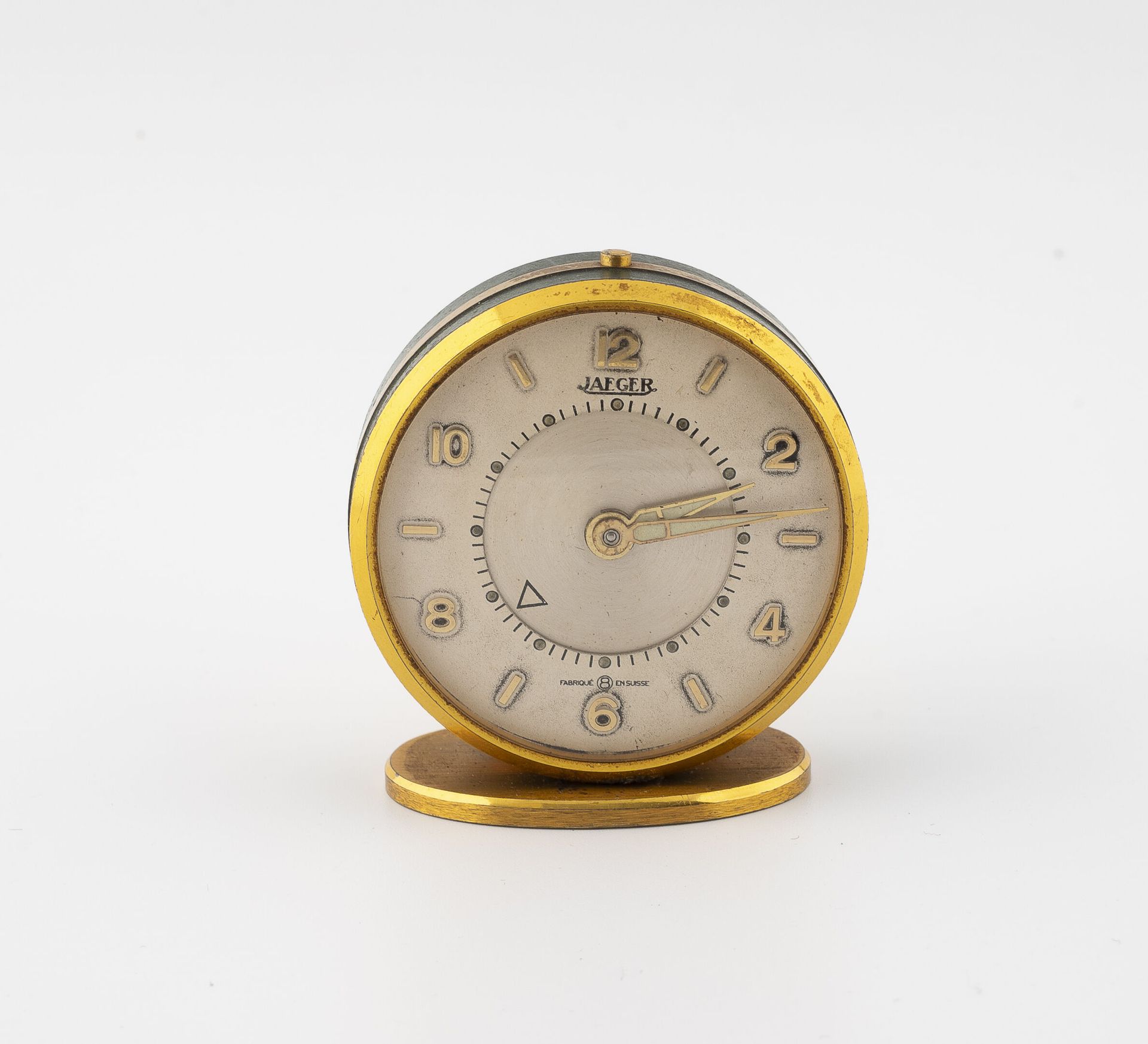JAEGER 鎏金金属和绿色漆面的旅行闹钟。 
白色背景的圆形表盘，有签名，金色阿拉伯数字的时针，轨道的分钟。
直径：46毫米。 
显著的磨损。
