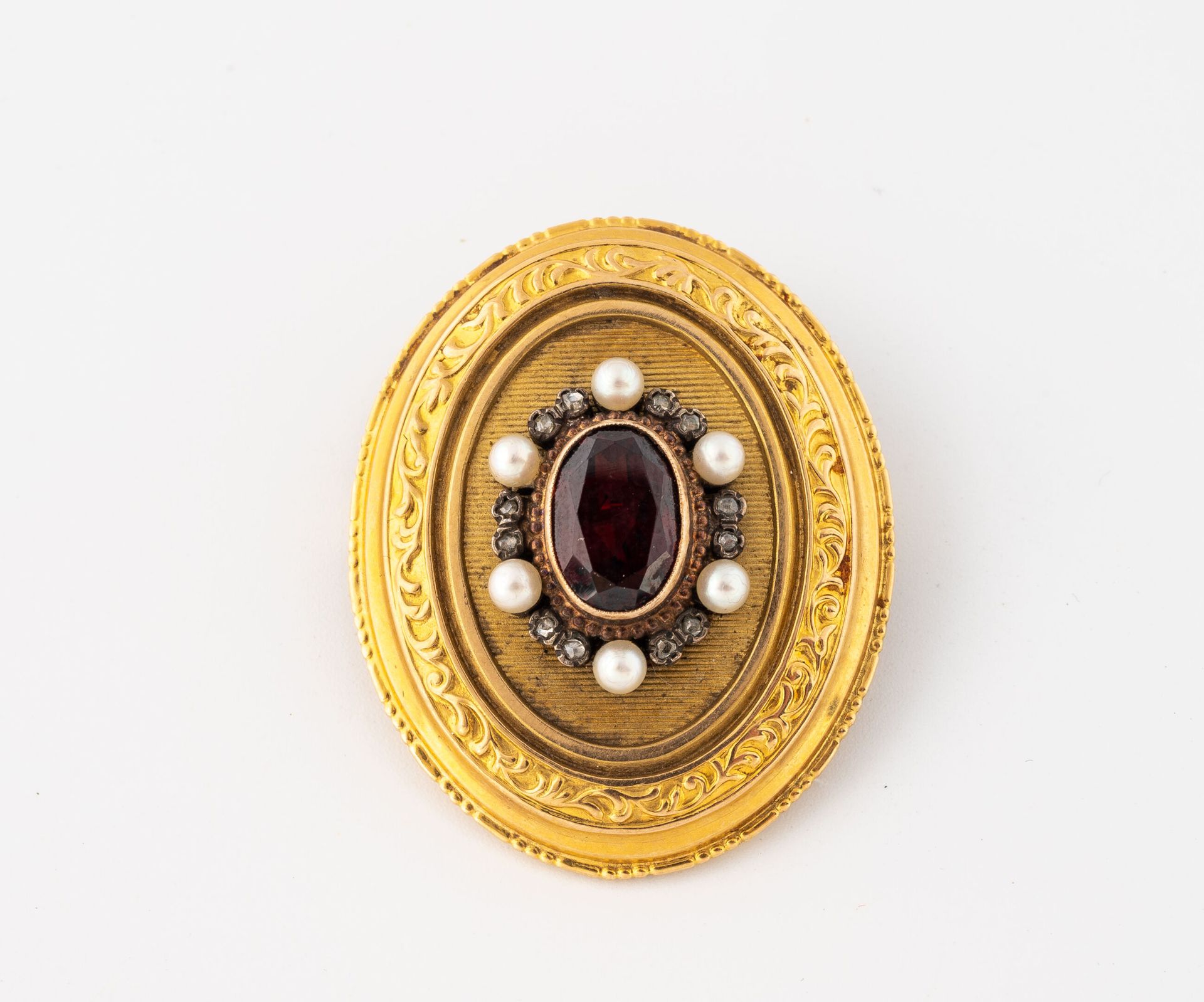 Null 黄金（750）勋章胸针，以椭圆形刻面石榴石为中心，镶嵌白色种子珍珠和小型玫瑰切割钻石。 
黄金（750）胸针。
毛重：9.4克 - 高3.3厘米。
有&hellip;