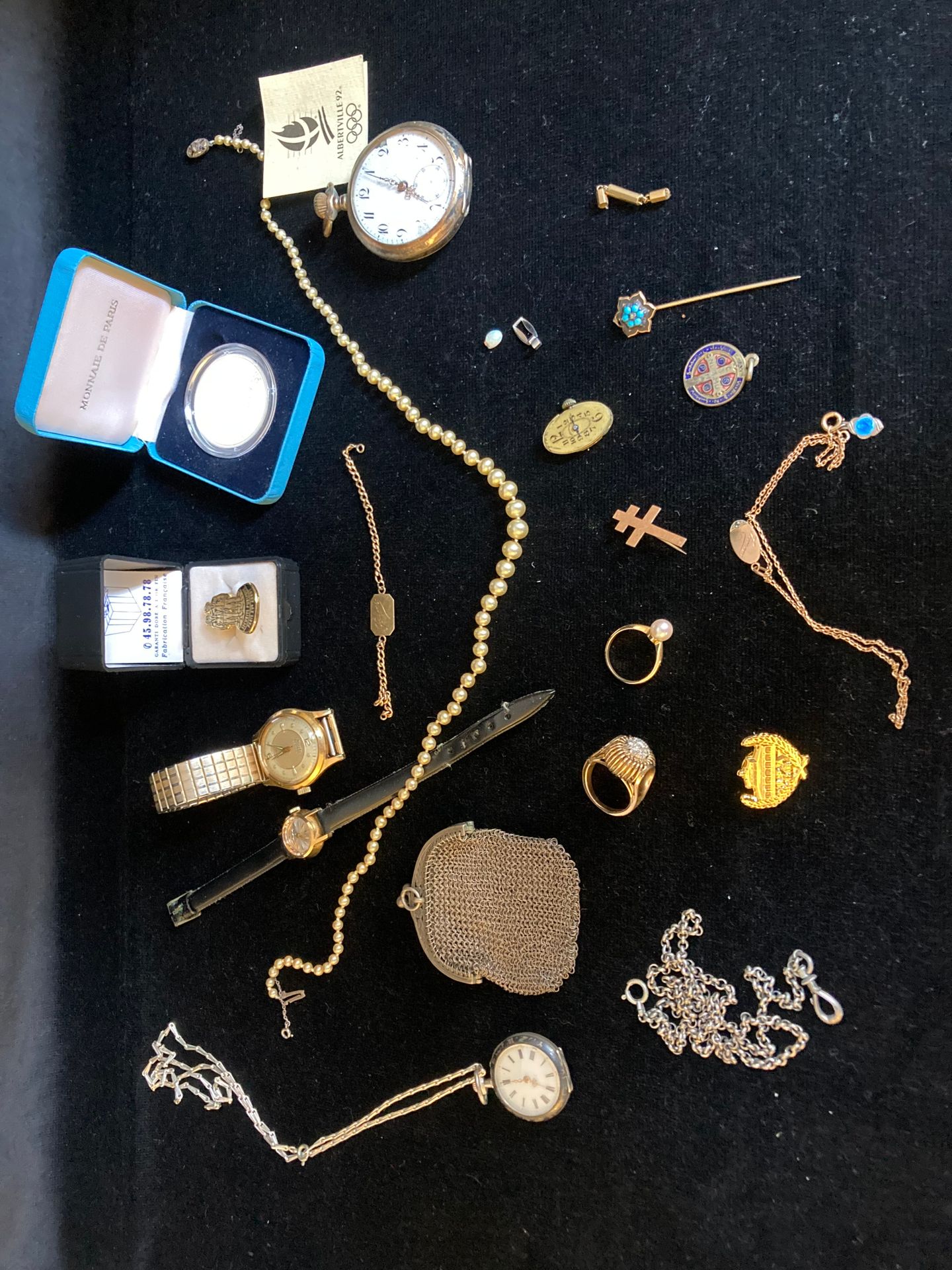 Null Modeschmuck, darunter eine Uhr aus Metall und eine Perlenkette.