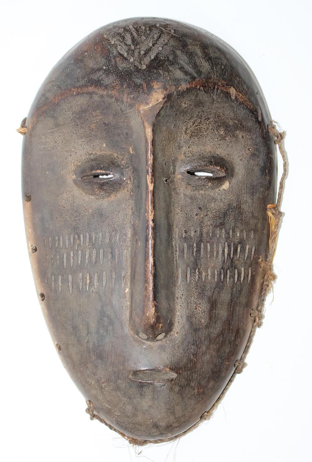 Lega Maske 有网状鼻子的旧面具。额头和脸颊上的纹身。凸起的眼珠，美丽的岁月痕迹。24厘米。 背面有收藏家的标签。 D