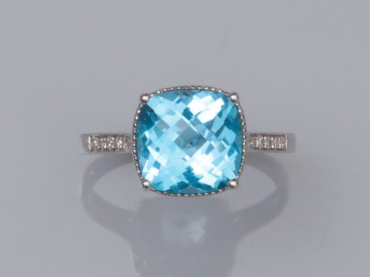 Null 白金750°/00（18K）戒指，镶嵌一颗约4.5克拉的枕形蓝色托帕石和小钻石。3.2 g.TDD 55.宽度：10.0毫米。鹰头拳。