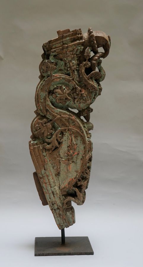 Null 一个用木头雕刻的建筑元素，带有红色和绿色的多色遗迹，上面装饰着树叶和花卷，还有一只张开翅膀的鸟。印度，18或19世纪。85x27厘米