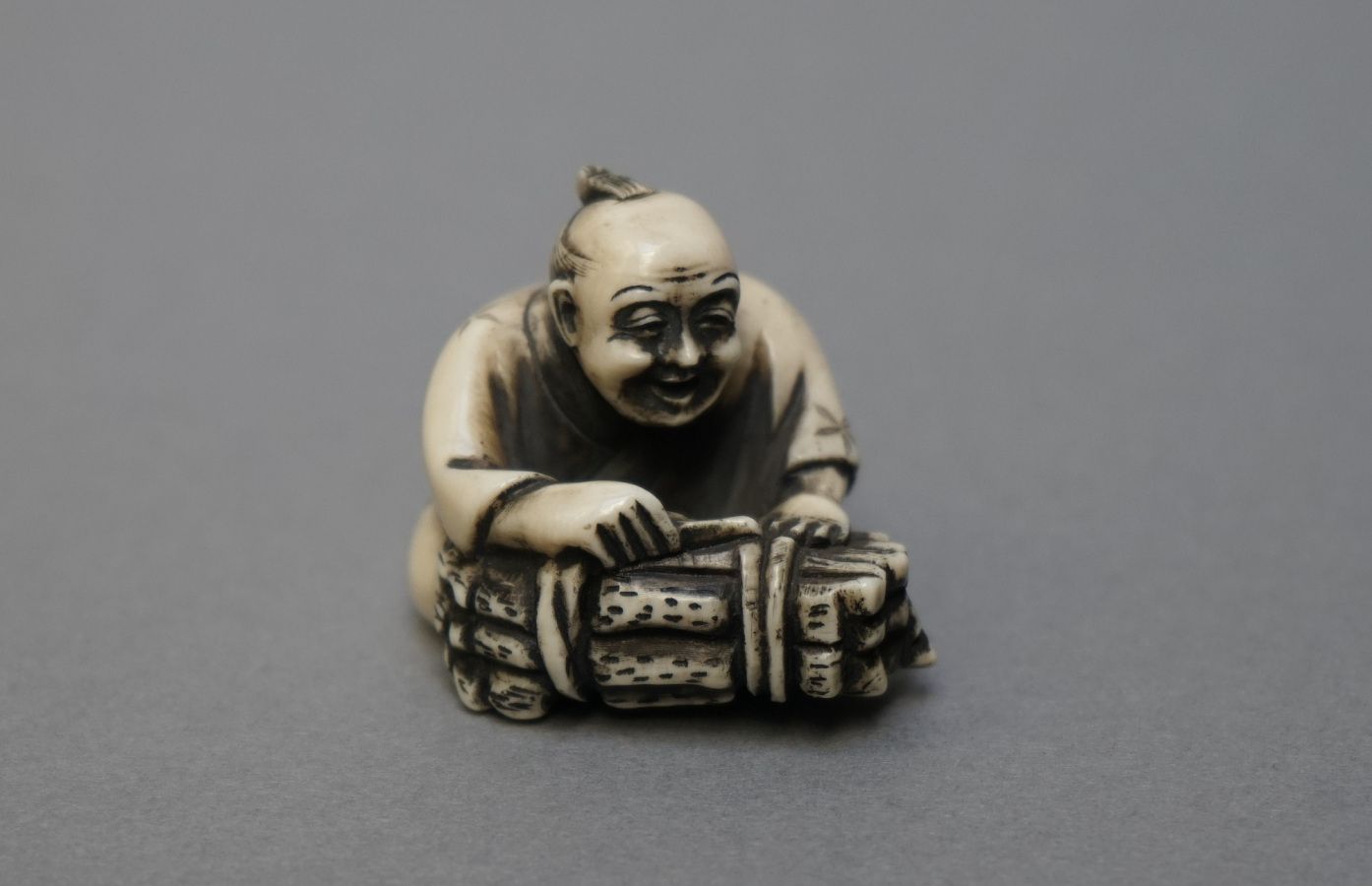 Null NETSUKE in patinated ivory showing an old man with a bundle. Signed. 

Japa&hellip;