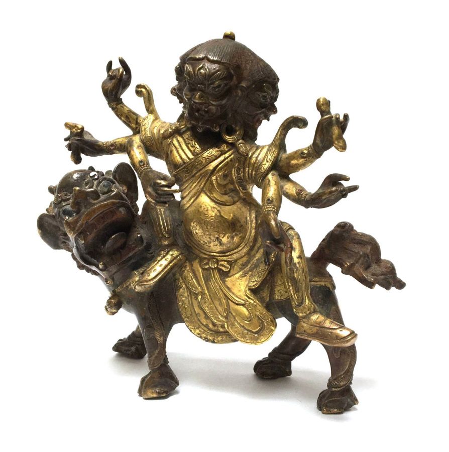 Null 一个三头六臂的守护神，骑着一头狮子。部分镀金的青铜。西藏-尼泊尔，19世纪。

高：13厘米；宽：14厘米