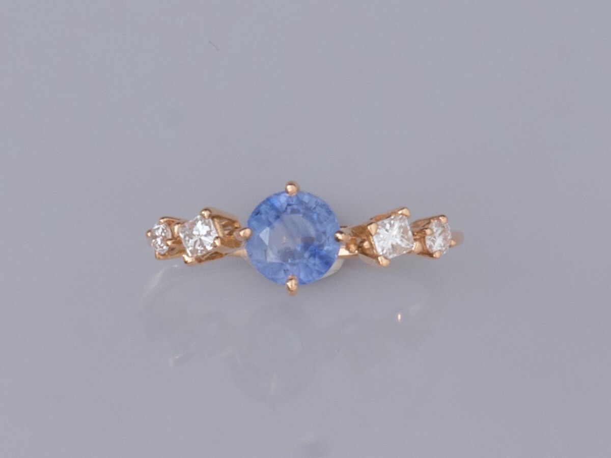 Null 750°/°(18K)黄金精致戒指，镶有一颗约0.90克拉的圆形蓝宝石，两侧各有一颗公主式切割钻石和一颗明亮式切割钻石。1.7 g.TDD 49.5.&hellip;