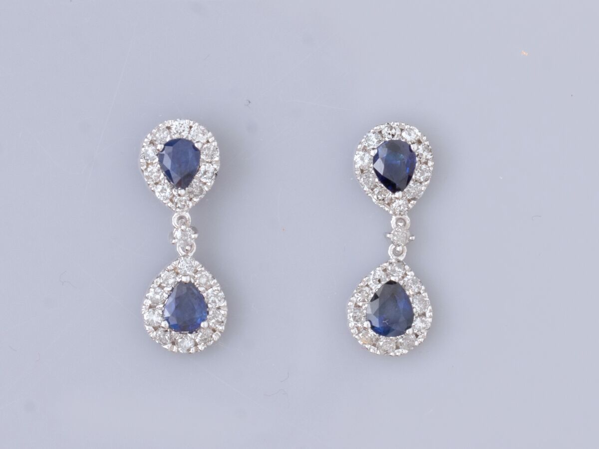 Null 18K白金耳环一对，镶嵌两颗梨形蓝宝石，周围有明亮式切割钻石。高度：2厘米。标有一个鹰头。