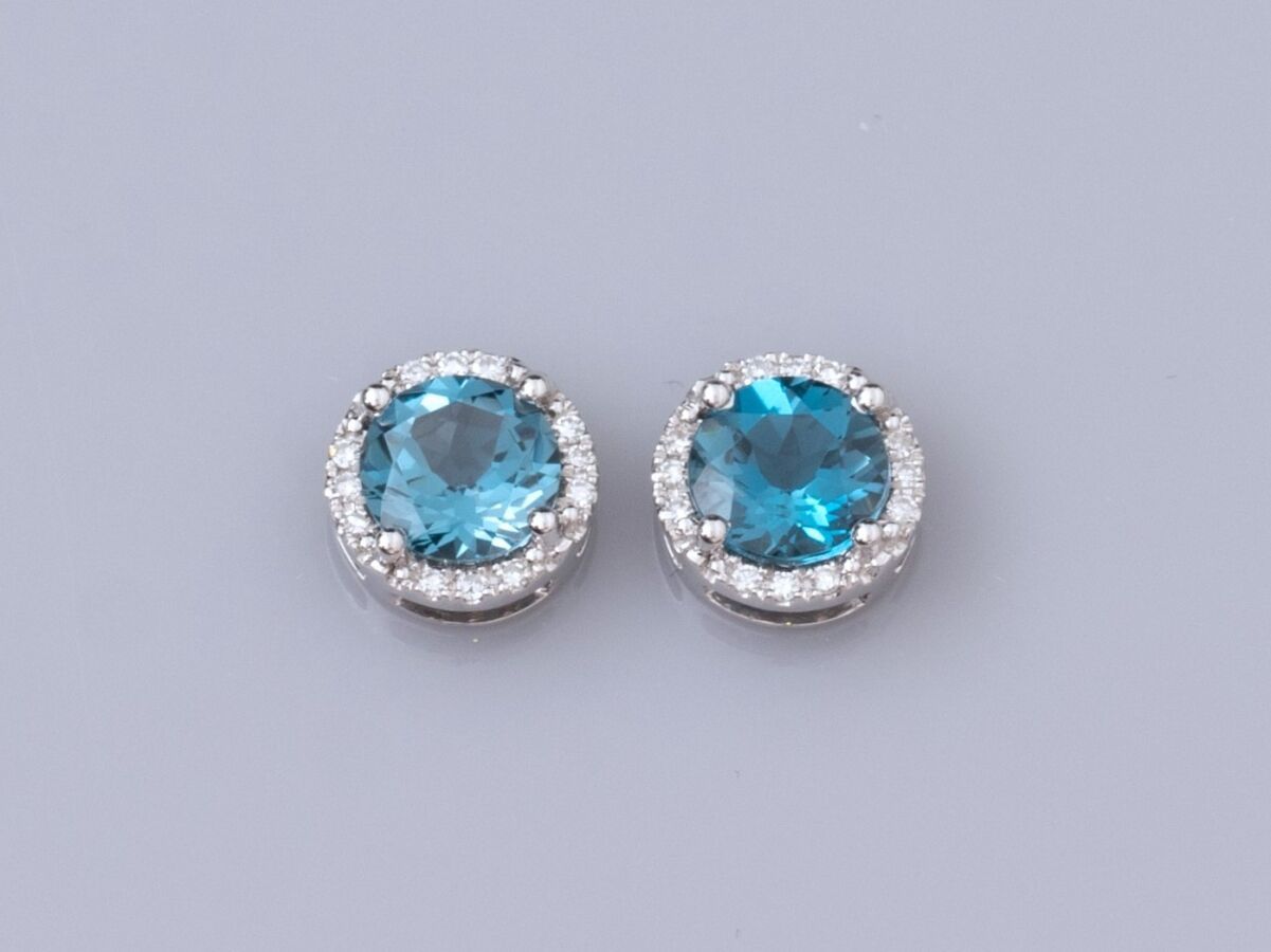 Null 一对18K白金耳环，每只耳环上都镶嵌着约1克拉的圆形刻面 "伦敦蓝 "黄宝石，周围是明亮式切割的钻石，重2.2克。高度：8.3毫米。推杆式扣件。鹰头标&hellip;