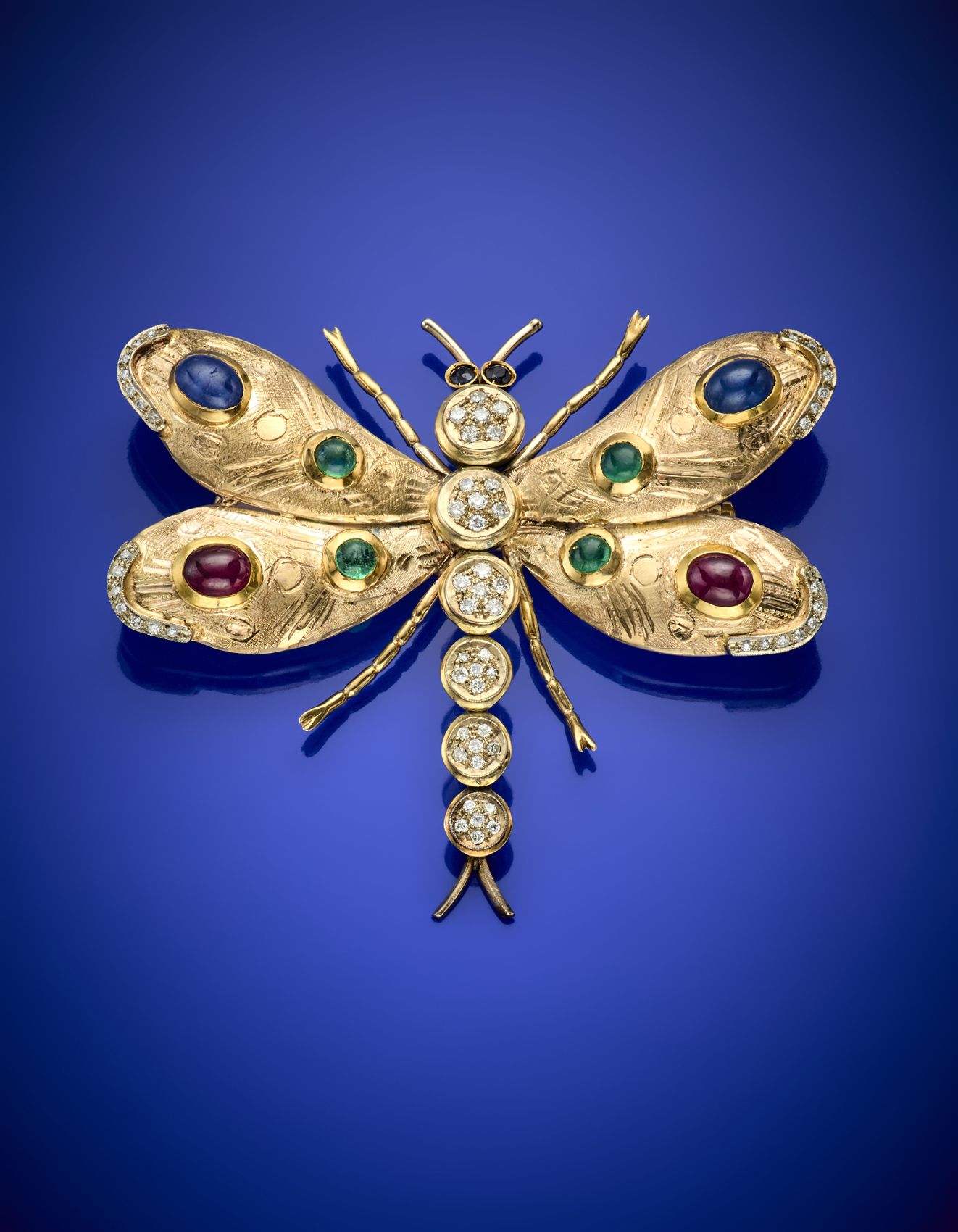 Null 双色9K部分凿纹金和钻石蜻蜓形胸针，以凸圆形蓝宝石、红宝石和绿宝石为点缀，重24.97克，宽6.50厘米左右。Cased by Serra Roma
&hellip;