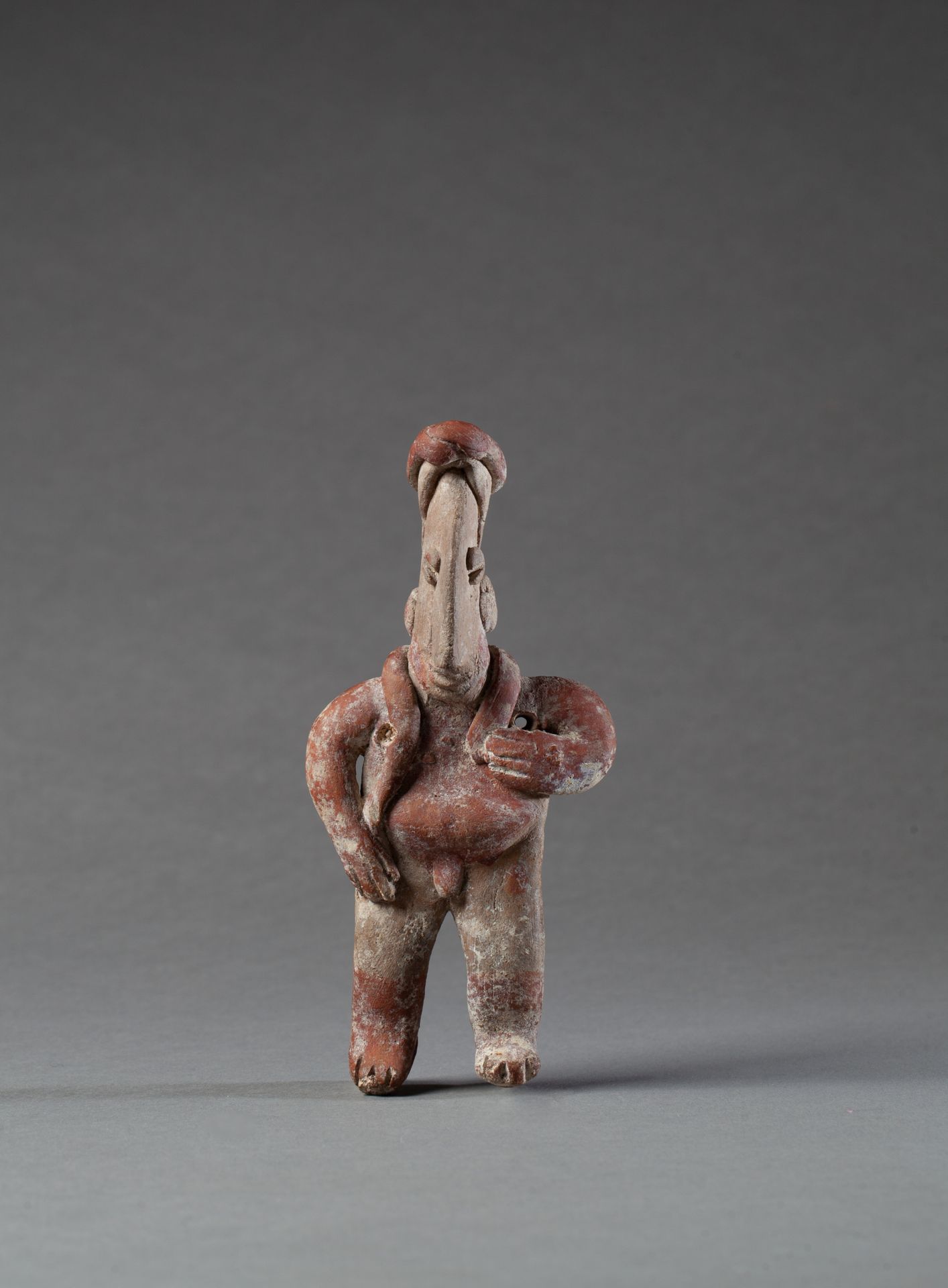 STATUETTE 显示了一个有着超大鼻子的人物，他的肩膀上扛着一条蛇。

米色和咖啡红色的陶土

墨西哥西部哈利斯科州，公元前100年-公元250年

14.&hellip;