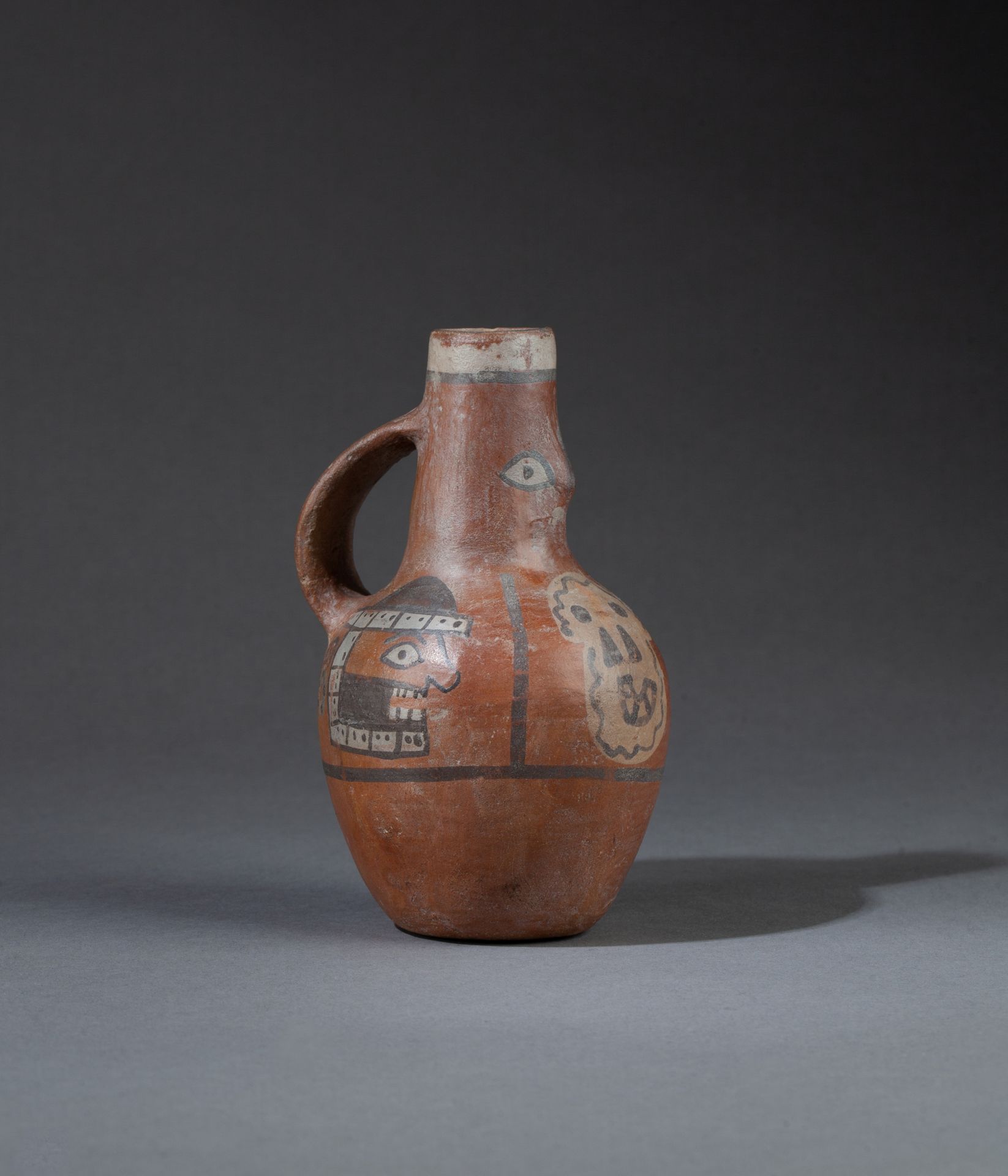 Vase 呈现出一个半身神像和三个有战争表情的战利品头像。 

多色赤土。

Huari，秘鲁，公元700-1000年。 

 14 x 7.5 cm