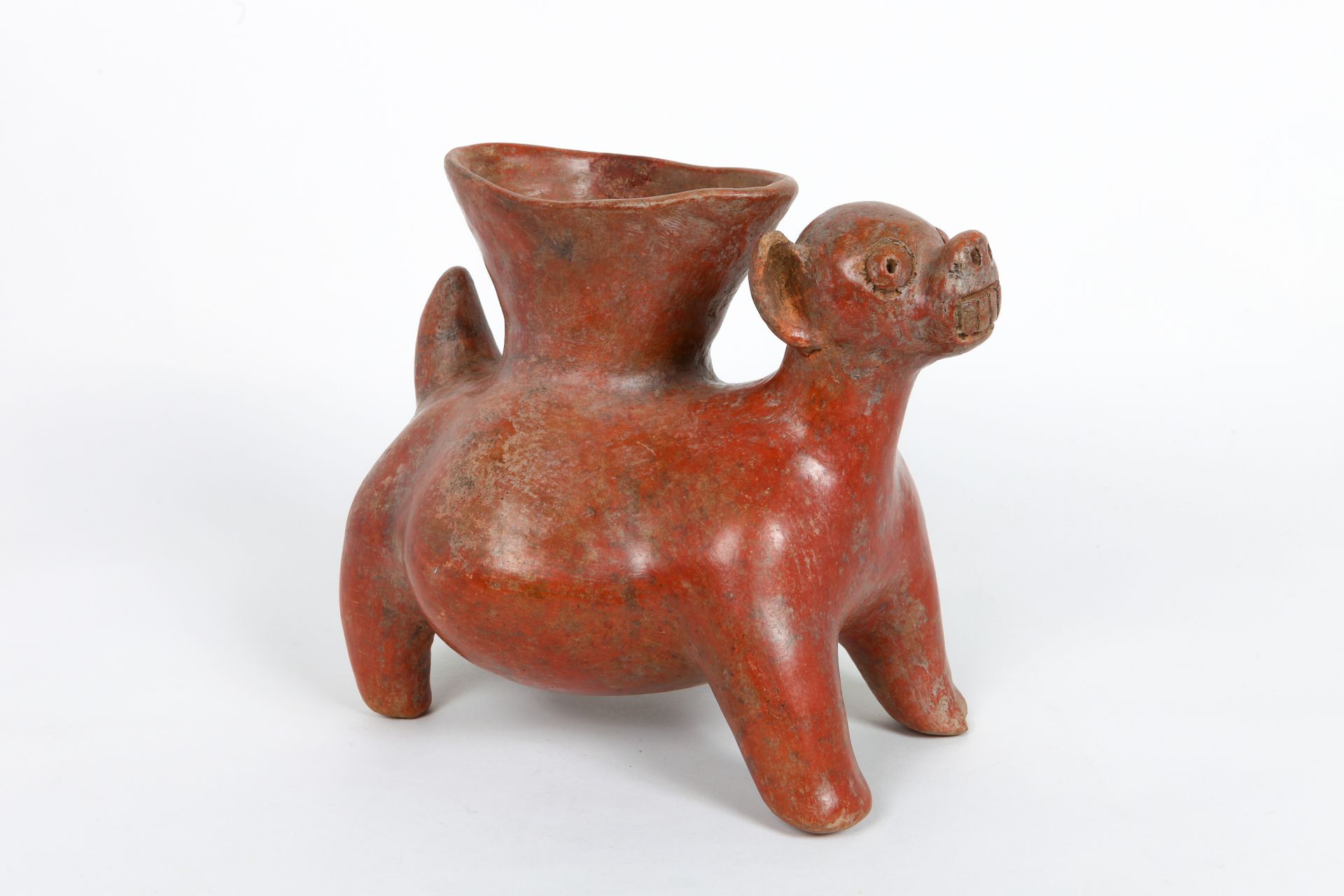 Vase 胖狗的形状，耳朵竖起来，嘴巴张开露出獠牙，以示保护。

橙色和咖啡红色的陶器，一只耳朵上有小缺口。

科利马，墨西哥西部，公元前100年至公元250年&hellip;