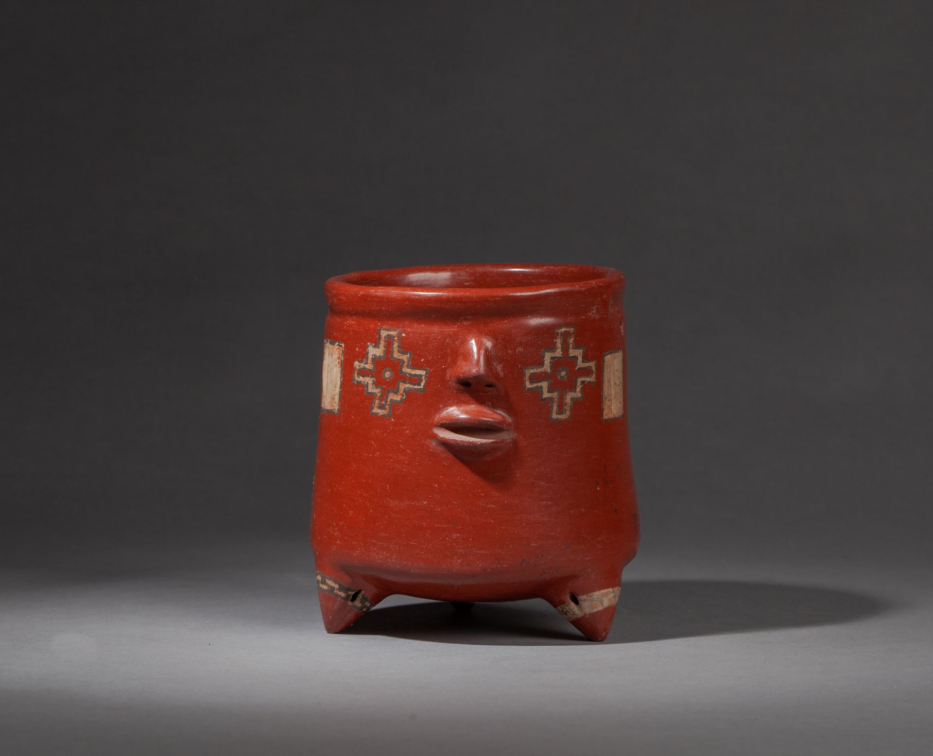 *Vase tripode cylindrique 
decorato con un volto umano schematico in rilievo. La&hellip;