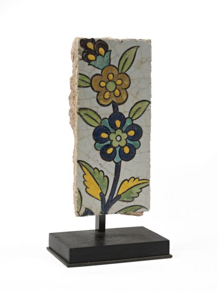Null 有花的瓷砖碎片，硅质糊状物，有cuerda seca或黑线的装饰。伊朗，17世纪，萨法维时期。瓷砖的尺寸：18 x 8厘米。带底座的总高度：23厘米。