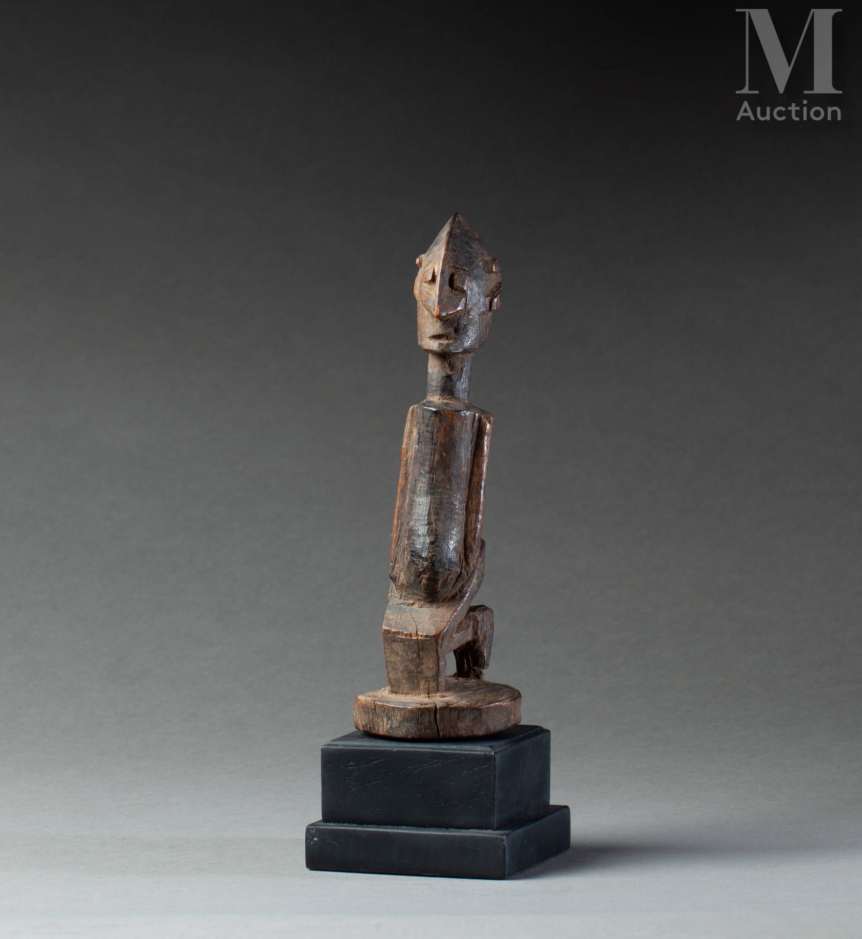 Statuette (Dogon) 显示了一个蹲着的人物，有长长的手臂，动物的耳朵和一个雕刻成箭头的鼻子。

硬木，古老的棕色和蜂蜜色泽。

多贡，马里，19世&hellip;