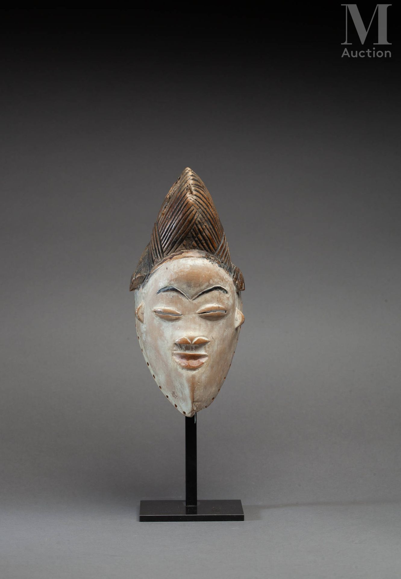 Masque Punu (Gabon) 面具上有一张表情丰富的脸，半闭着眼睛，有一个三叶的头饰。

木头，白色颜料和红赭石，古老的光泽和使用的痕迹。

普努，加&hellip;