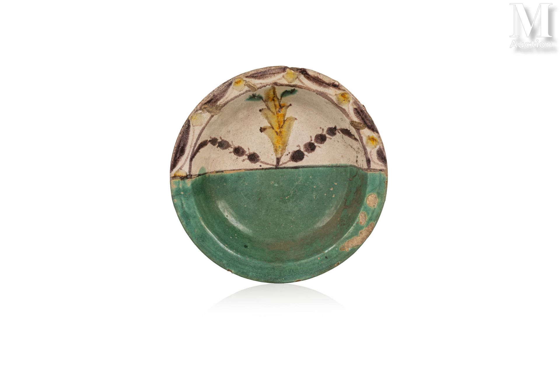 Assiette qallaline 突尼斯，突尼斯，19世纪末。

乳白色背景的绿色和棕色双色陶瓷盘。盘子的一半是平坦的绿色背景，而另一半是植物和赭石的装饰。&hellip;