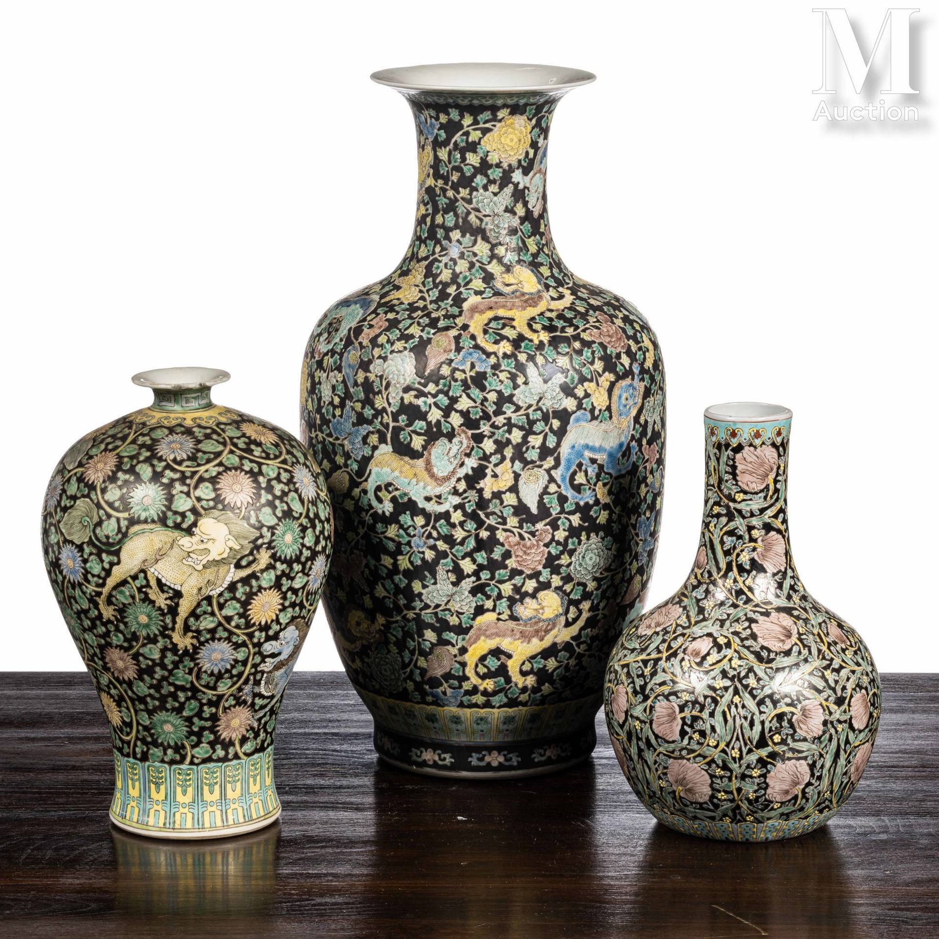 CHINE, XXe siècle 一套三个瓷瓶，分别是梅花形、柱形和瓶形，用黑色家族珐琅装饰，两个是莲花卷中的嵌合体，一个是鲜花。 

高度：34.5至59厘&hellip;