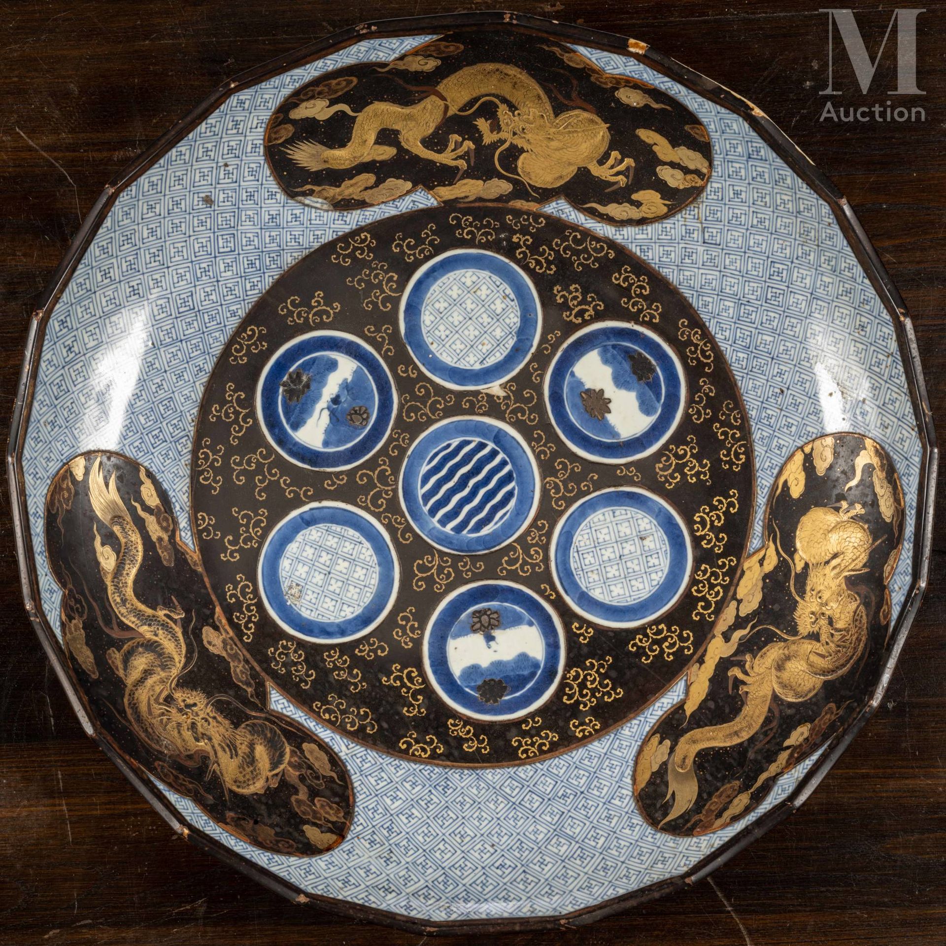 JAPON, XIXe siècle 青花瓷和黑金漆有田大盘，中间饰有圆形徽章，边缘饰有三叶草图的龙，背景衬以几何图案。

直径：52厘米

裂缝