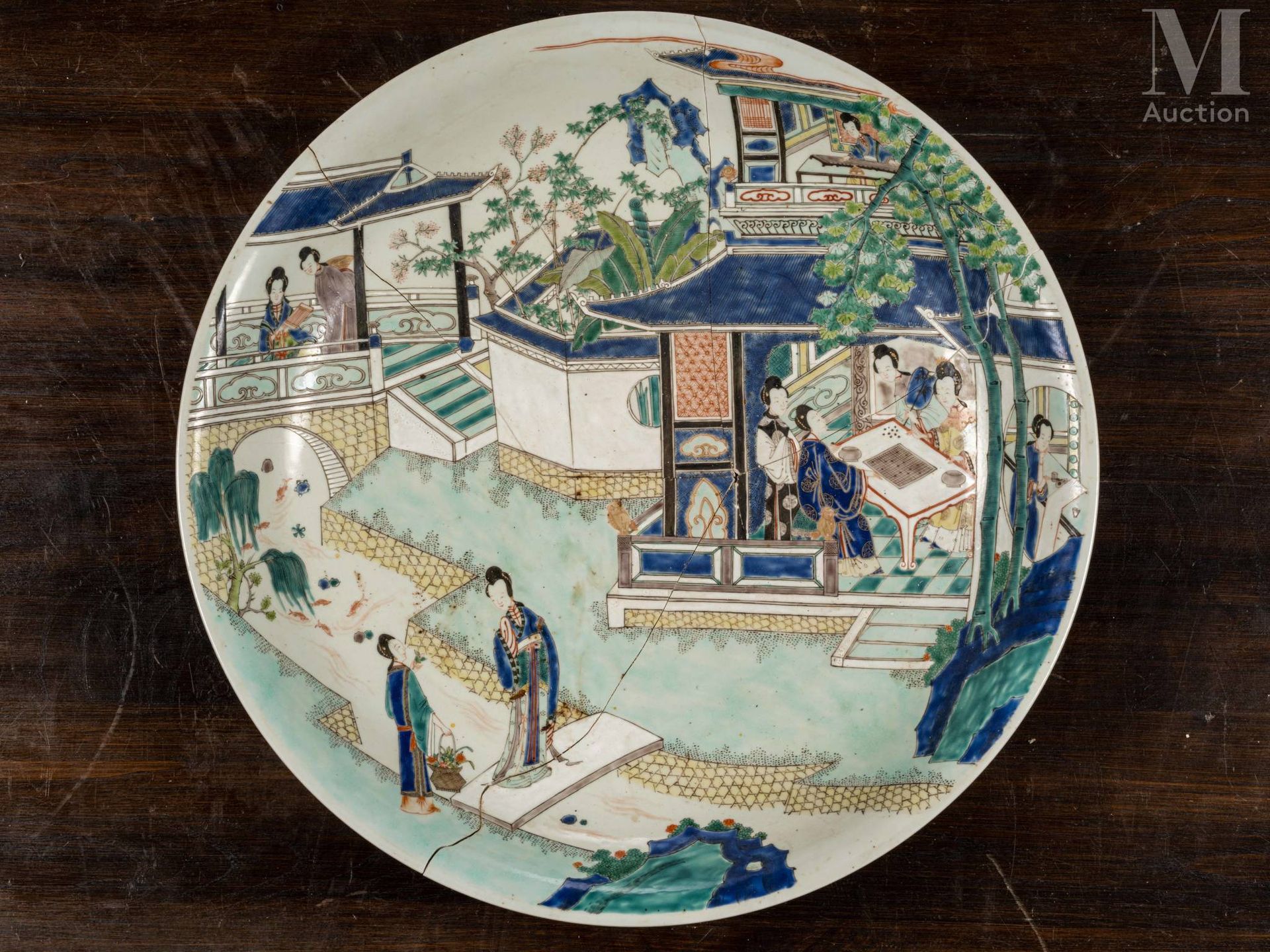 CHINE, Epoque Kangxi, XVIIIe siècle 一个大的圆形弧形瓷盘，用绿色家族珐琅彩装饰着室内和花园里的几位优雅女士。 底下有康熙款的&hellip;