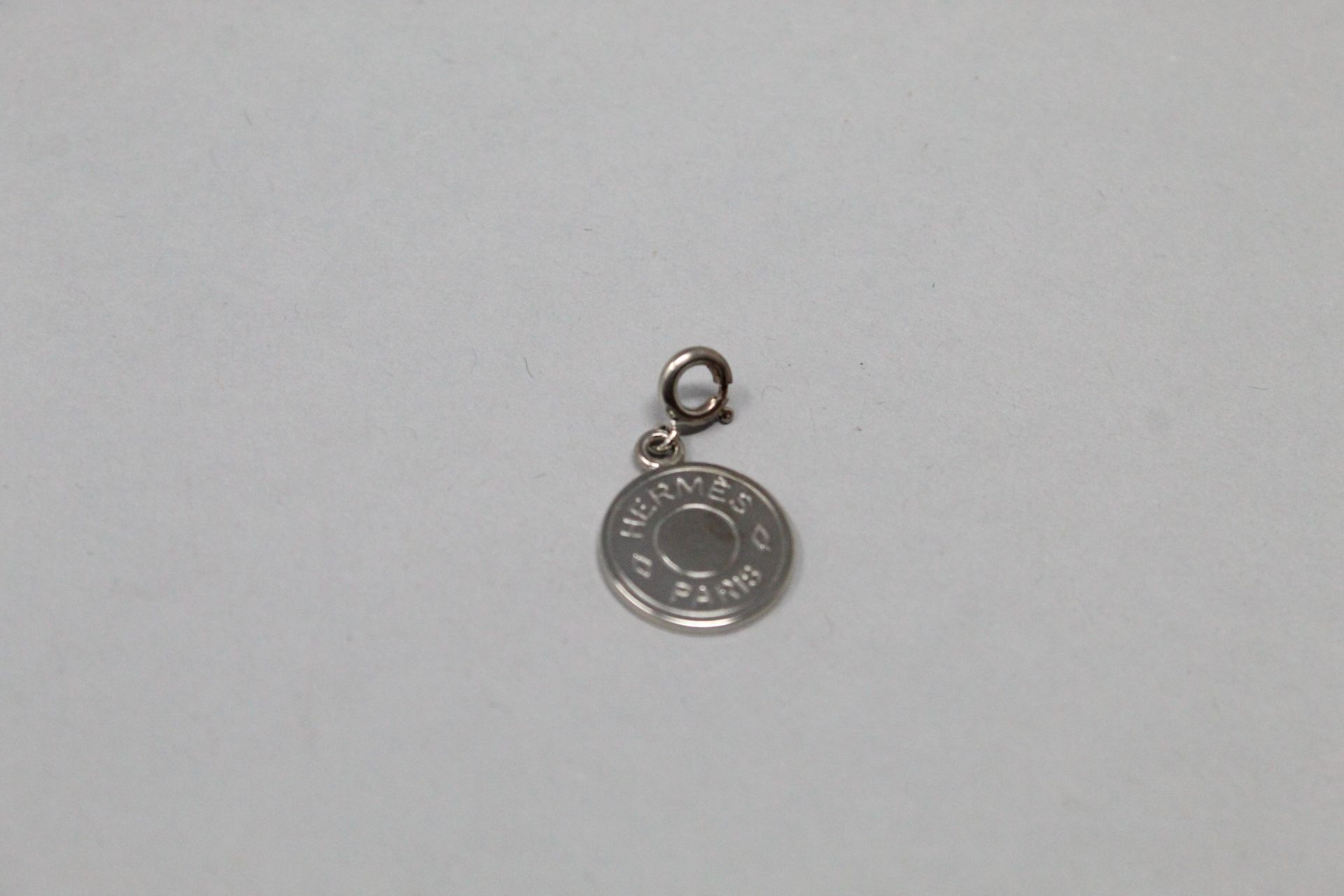 Null HERMES Paris

Pendentif de forme circulaire en métal argenté, portant l'ins&hellip;