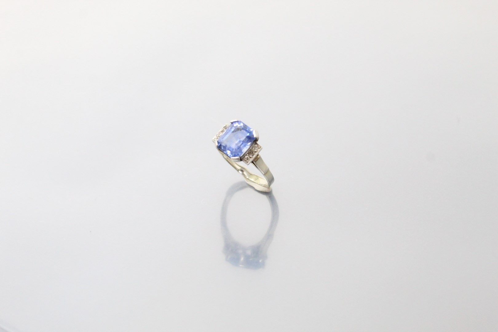 Null 18K（750）白金和铂金戒指，镶嵌着一颗长方形切割的浅蓝色蓝宝石（颜色不均匀），上面镶嵌着一排8/8和老式切割的钻石（一颗破碎）。

打击鹰头、狗头&hellip;