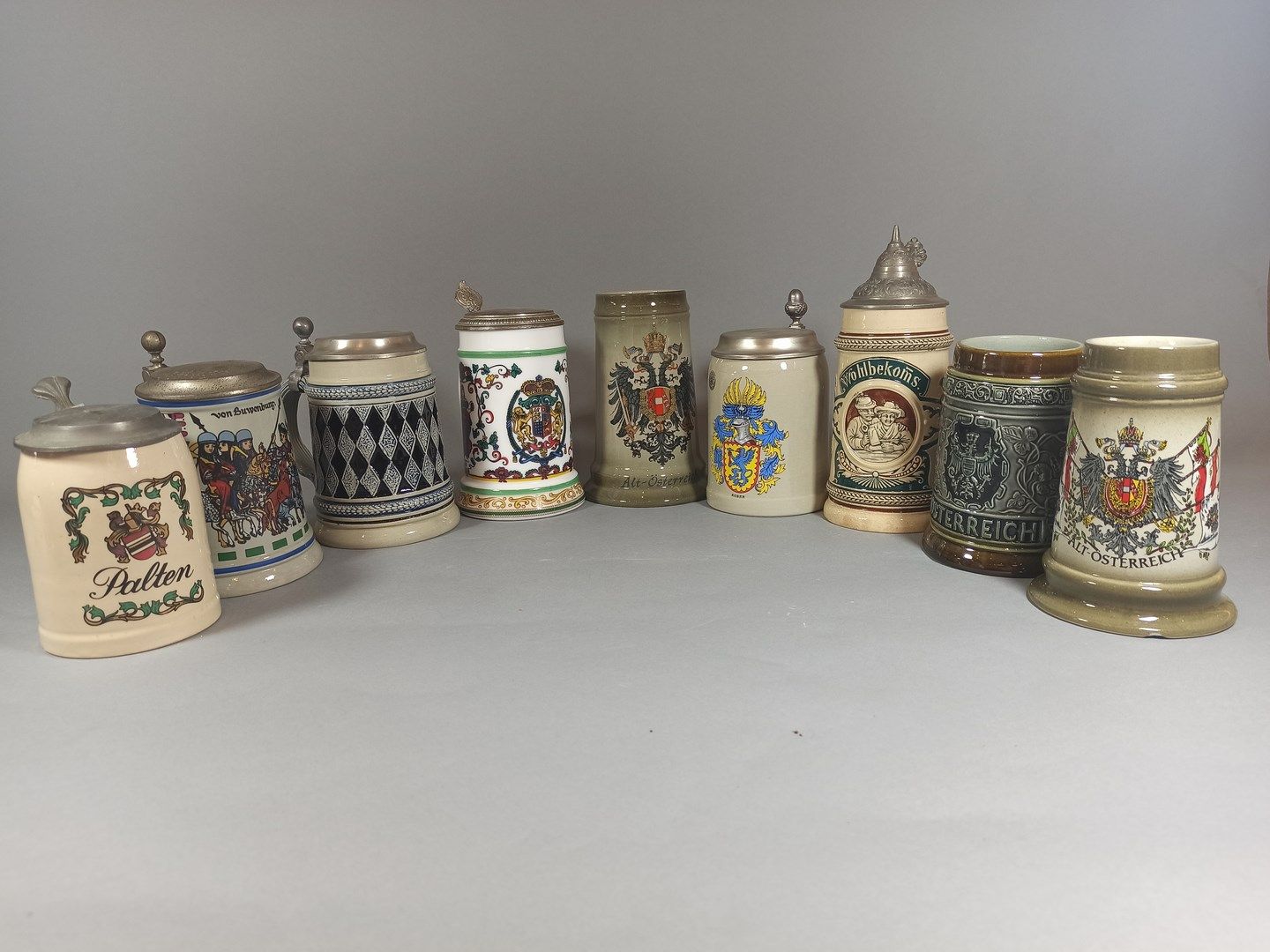 Null 德国和奥地利的工作。

一套9件珐琅彩炻器和瓷器啤酒杯，装饰有纹章、侠义场景、酒馆场景和几何装饰。

(事故发生在一人身上)