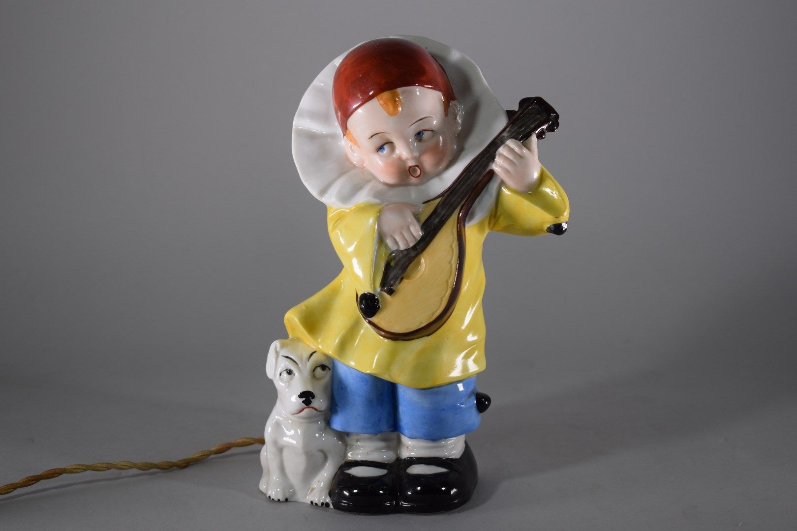 Null 多彩瓷器夜灯的主角是一个装扮成皮耶罗的孩子，正在弹奏吉他，他的脚下是一只狗。德国作品，约1930年。时代电气化，电木元件（不保证）。

高度：20厘米&hellip;