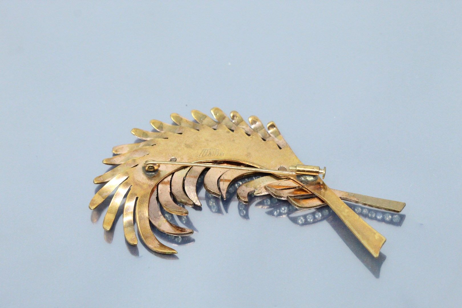 Null 镂空羽毛形式的鎏金金属胸针，其中一枚铺有白色宝石（缺失）。

高度：8.5厘米。高8.5厘米。
