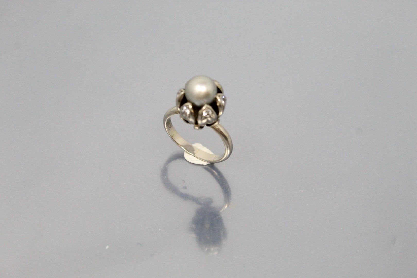 Null 18K（750）白金戒指，形成一朵花，叶子上装饰有钻石，纽扣由中心的珍珠形成。

手指大小：54 - 毛重：8.47克。