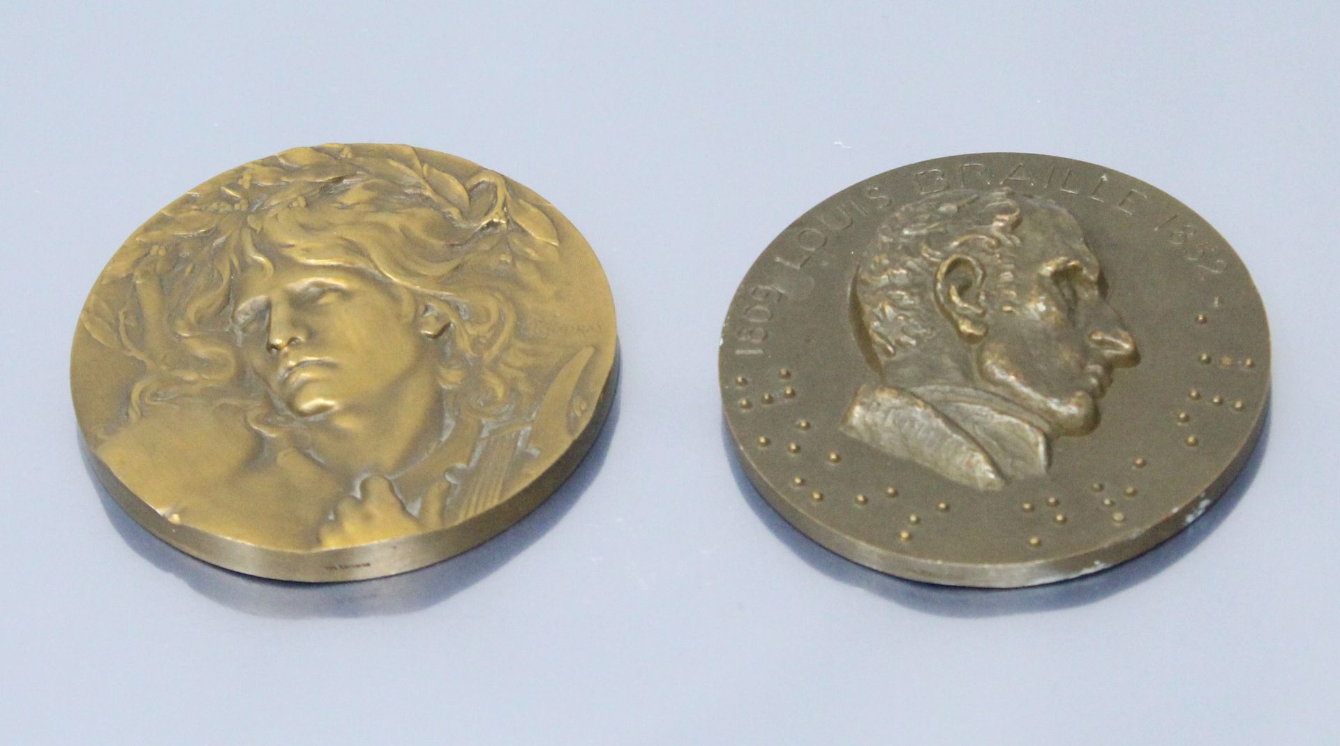 Null Dos medallas de bronce en la mesa.

- Louis Braille de perfil derecho 1809-&hellip;