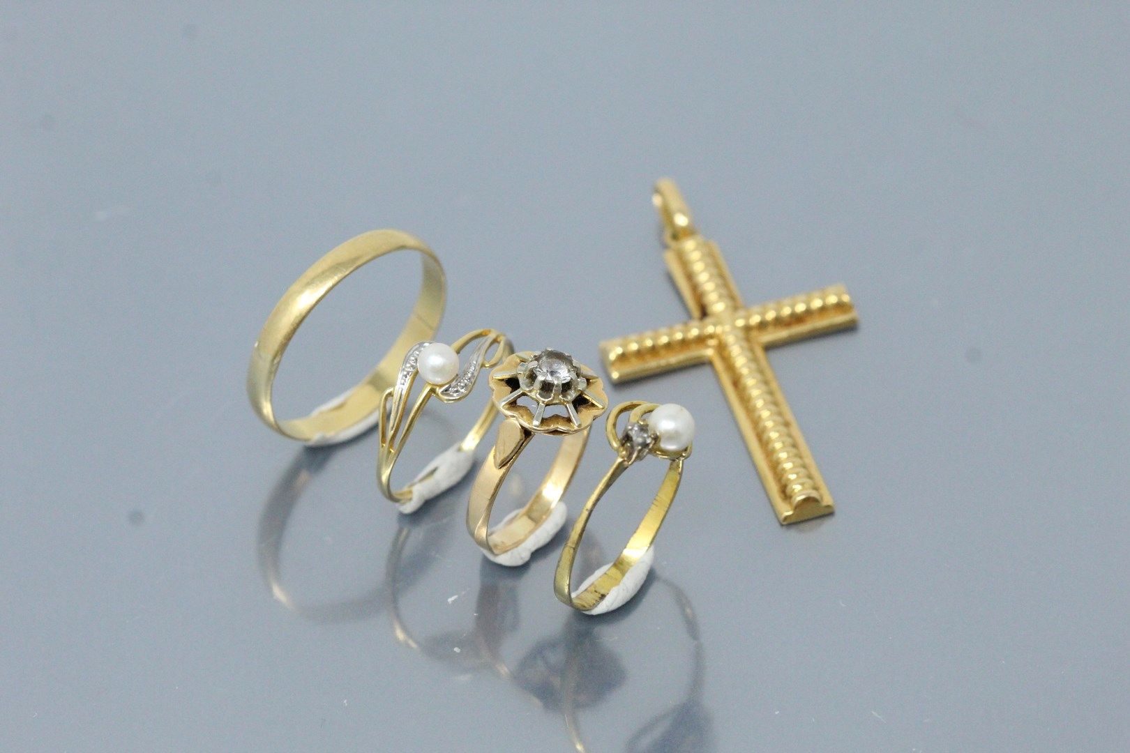 Null 一件18K(750)黄金小珠宝，包括一个十字架吊坠，一个结婚戒指，一个珍珠戒指和一个白石戒指。

毛重：7.99克。

附有一个带珍珠的银环。

重量&hellip;