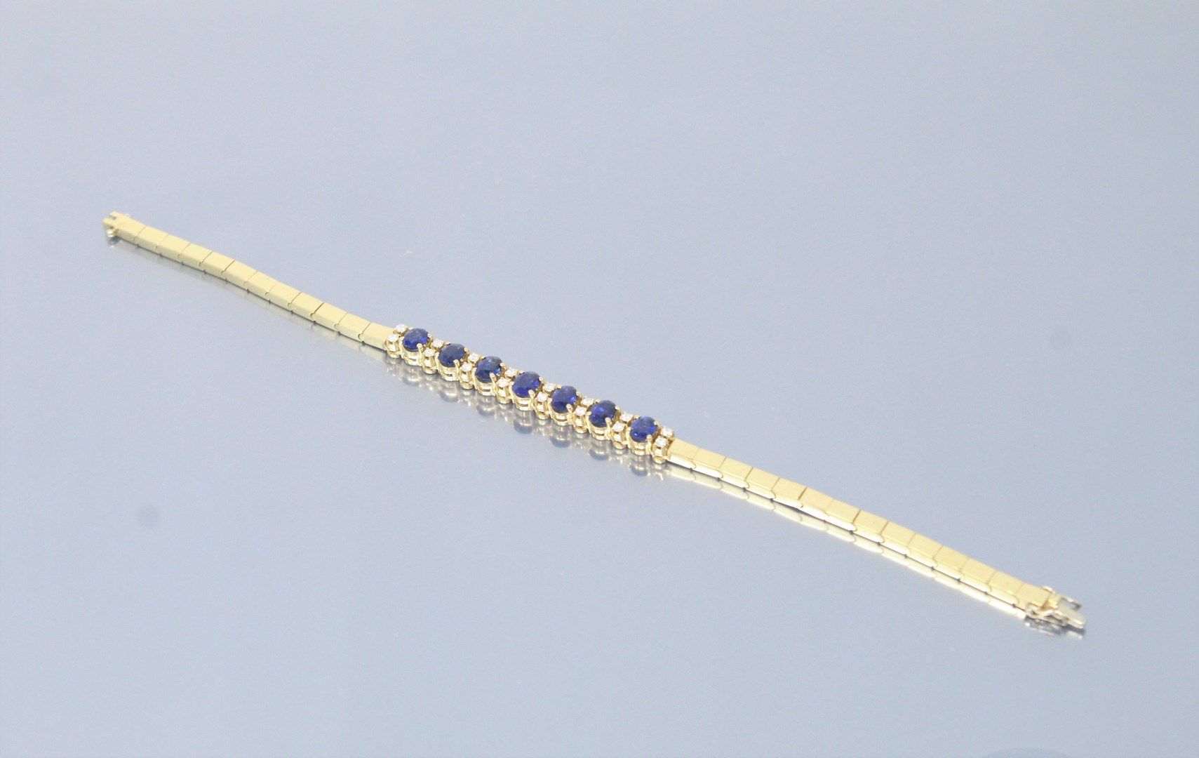 Null 18K(750)黄金铰链式手镯，以交替的椭圆形（加热）蓝宝石和明亮式切割钻石为中心，棘轮扣具有双重安全性。

长度：19厘米。- 毛重：17.67克。