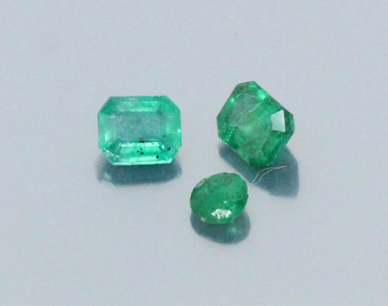 Null Lot of three emeralds, two rectangular with cut sides, another round on pap&hellip;