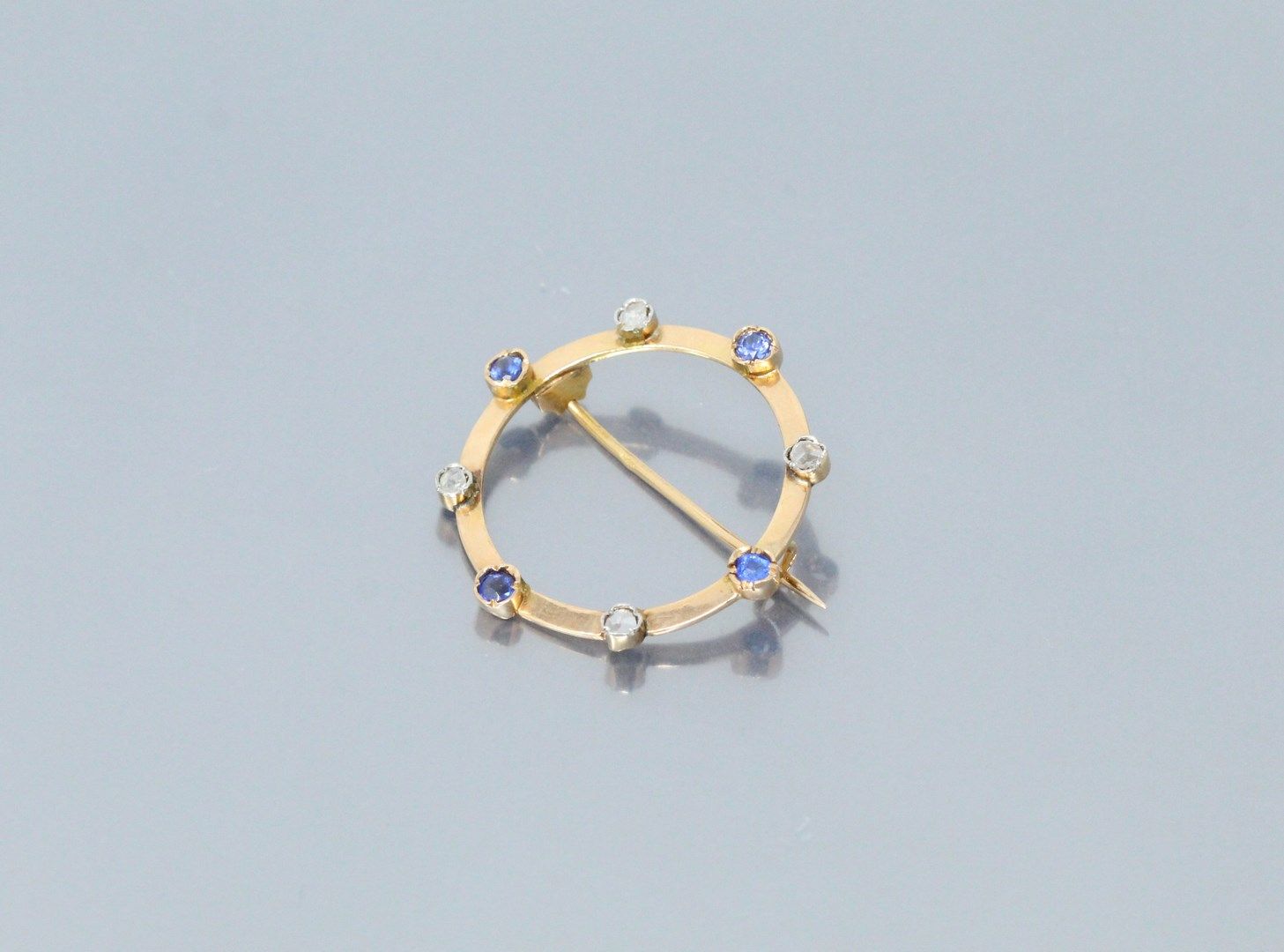Null 18K（750）黄金圆形胸针，镶嵌老式切割钻石和合成蓝宝石。

主体标记的痕迹。

马头标志。

直径：33毫米。- 毛重：4.20克。